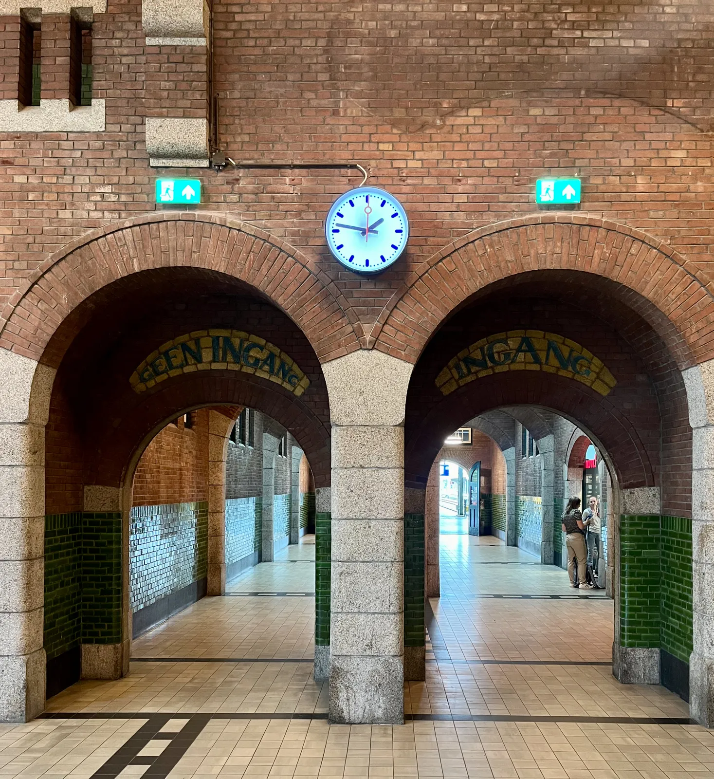 Peeking though two brick archs. The one on the left says, in wonderful typography made from tiles, that this is not an entry, while the one on the right says it is. Above these archs there’s a clock which points at 13 minutes to two. 