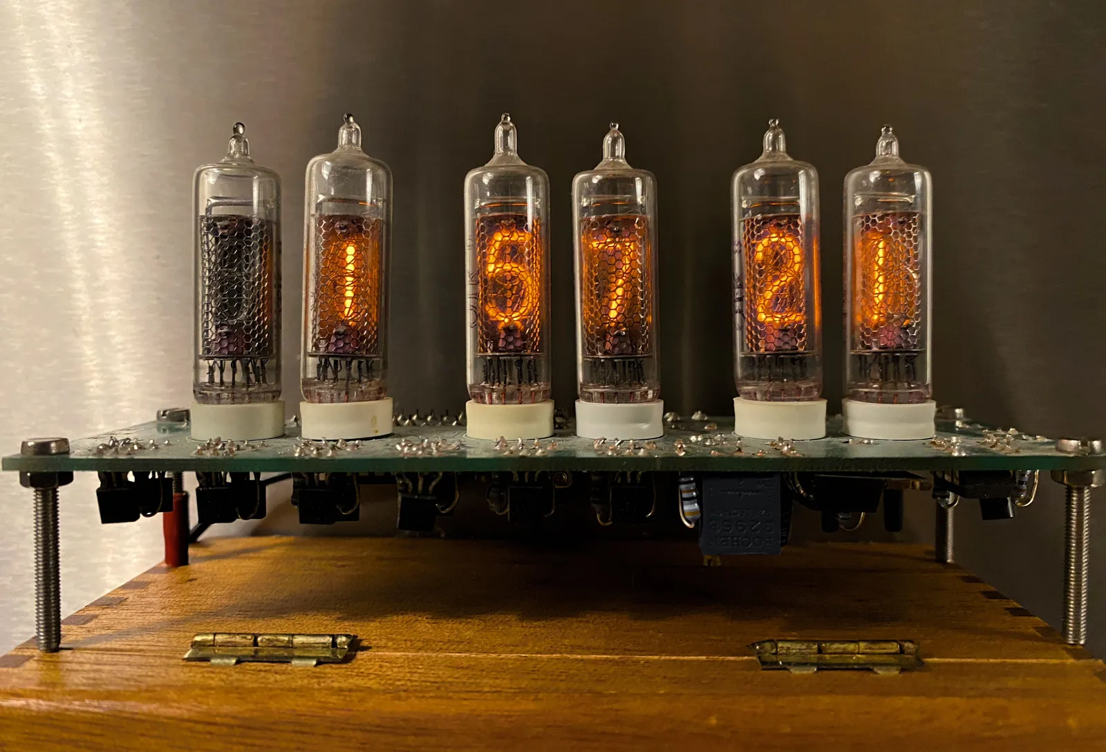 A clock made from glass tubes, with glowing pieces of iron in them. The clock says it is 1 hour, 57 minutes and 21 seconds.