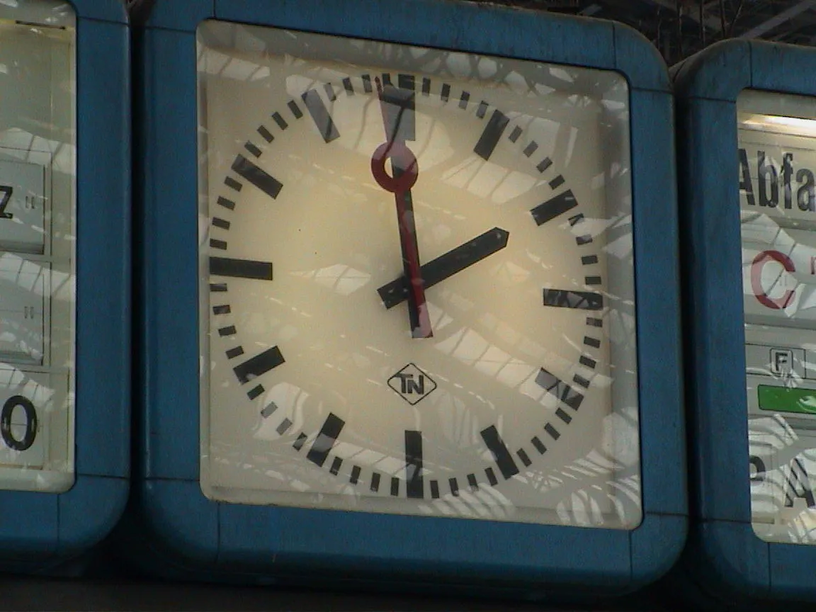 This modernist clock on a train station points at one minute to two.