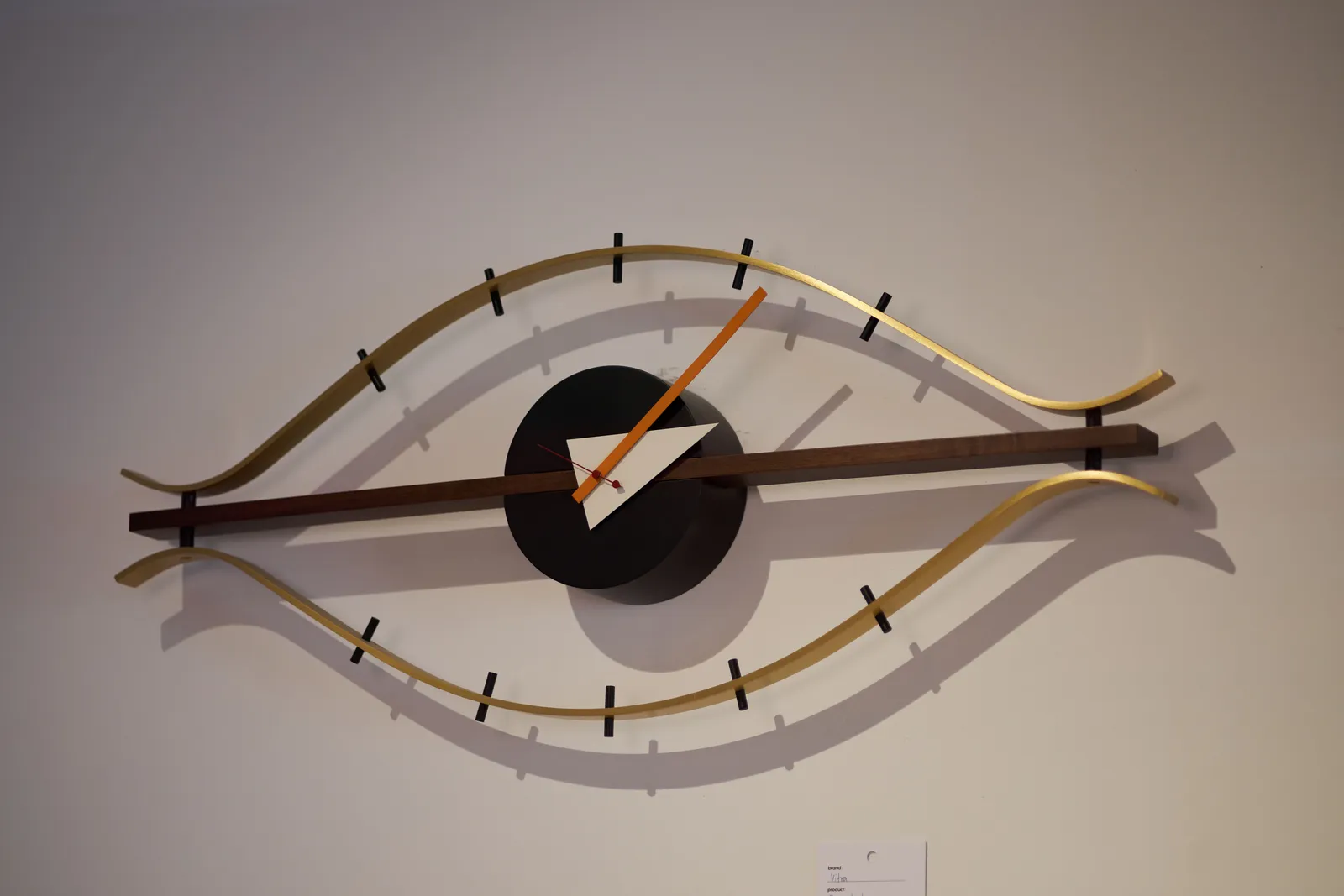 An abstract clock shaped in the form of an eye seems to point at approximately 6 minutes past 2.