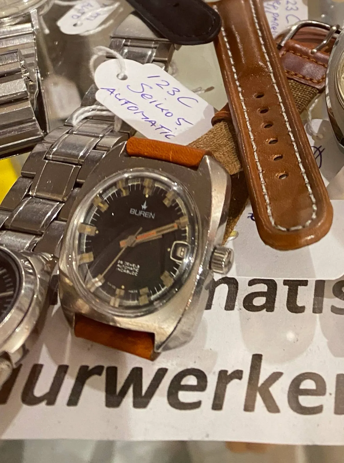 A few wrist watches for sale. Just one of them is clearly in focus. It points at 10 past 2.