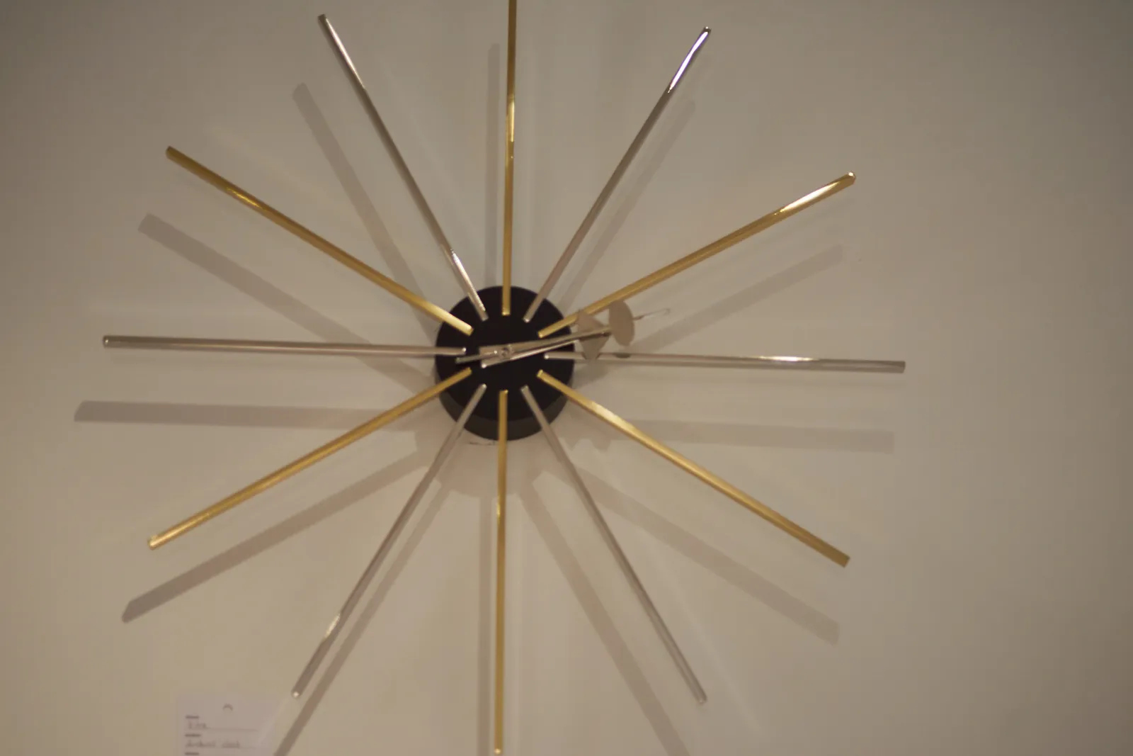 A clock with silver and golden sticks that indicate the five minute marks points at approximately 12 past 2.