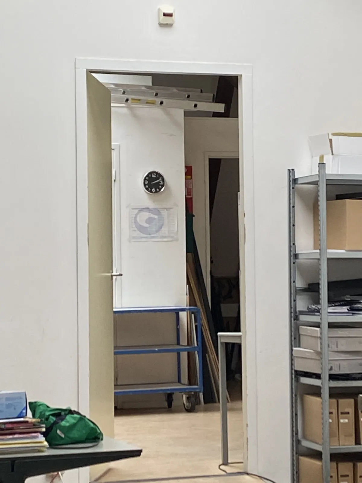 Peeking through a door. You can see a clock there. On it it is 12 past 2.