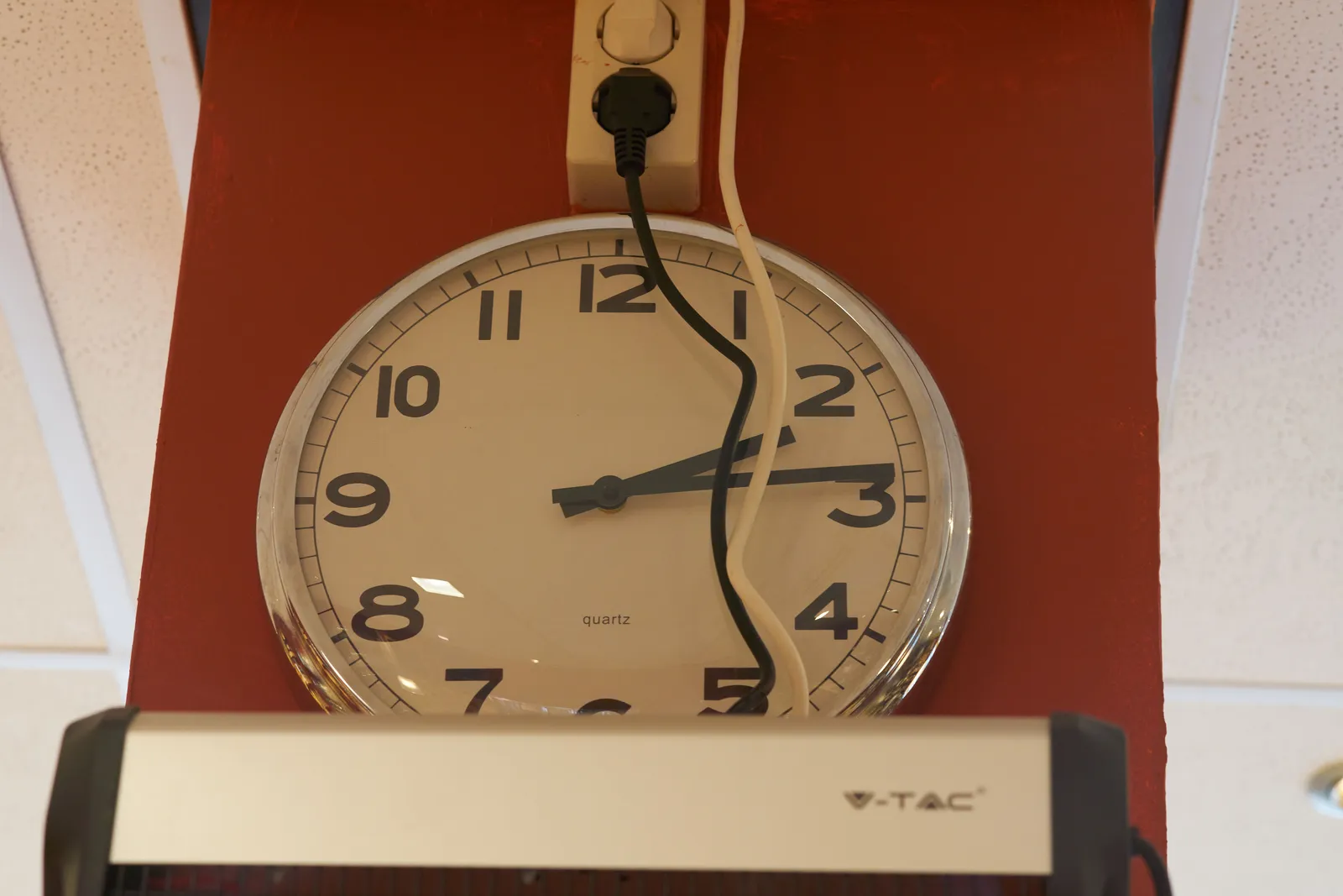 A clock, muffled away behind some wires, points at 14 past 2.