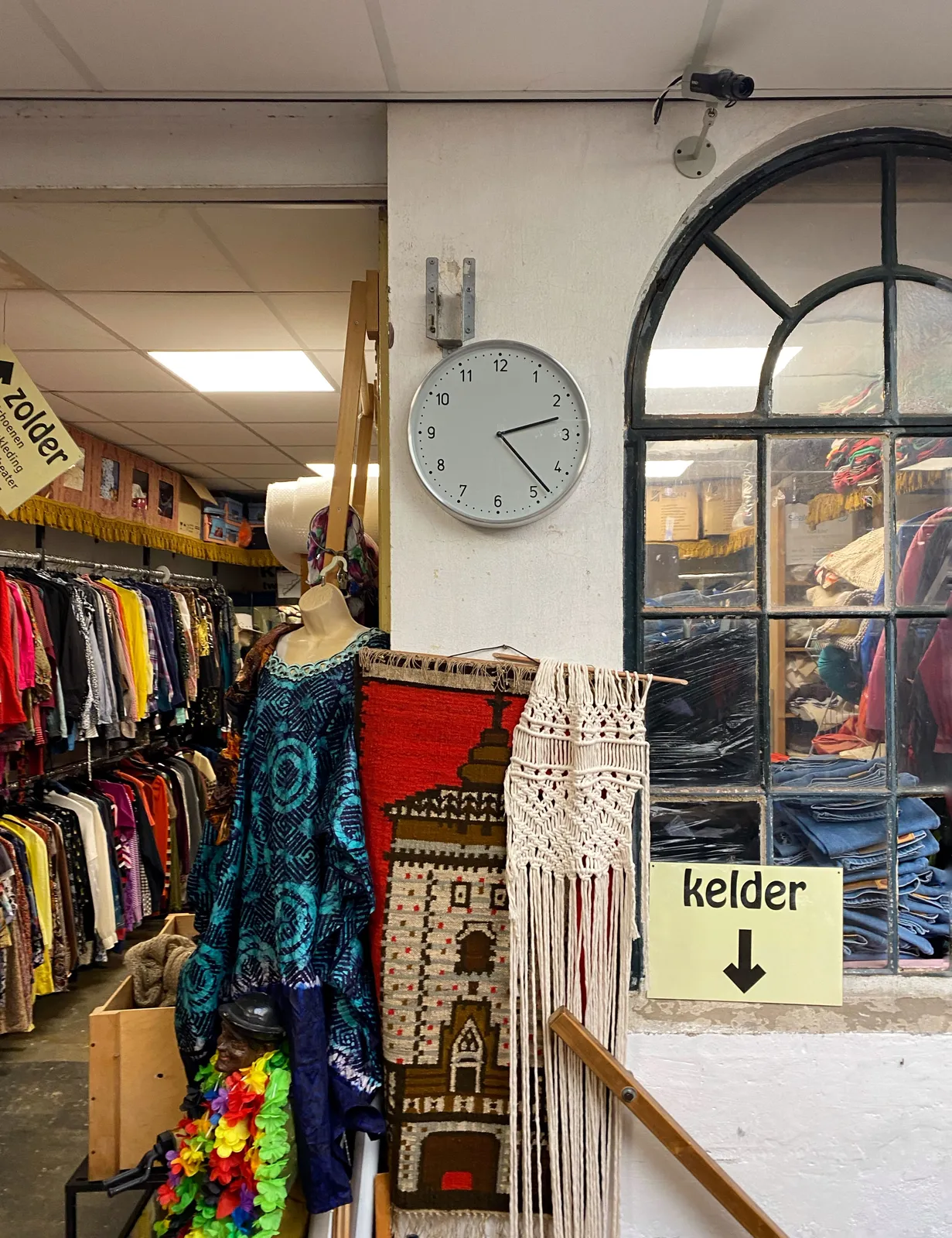 Lots and lots of clothes for sale. And a sign that points down, to the basement. There’s also a clock that points at 23 minutes past 2.