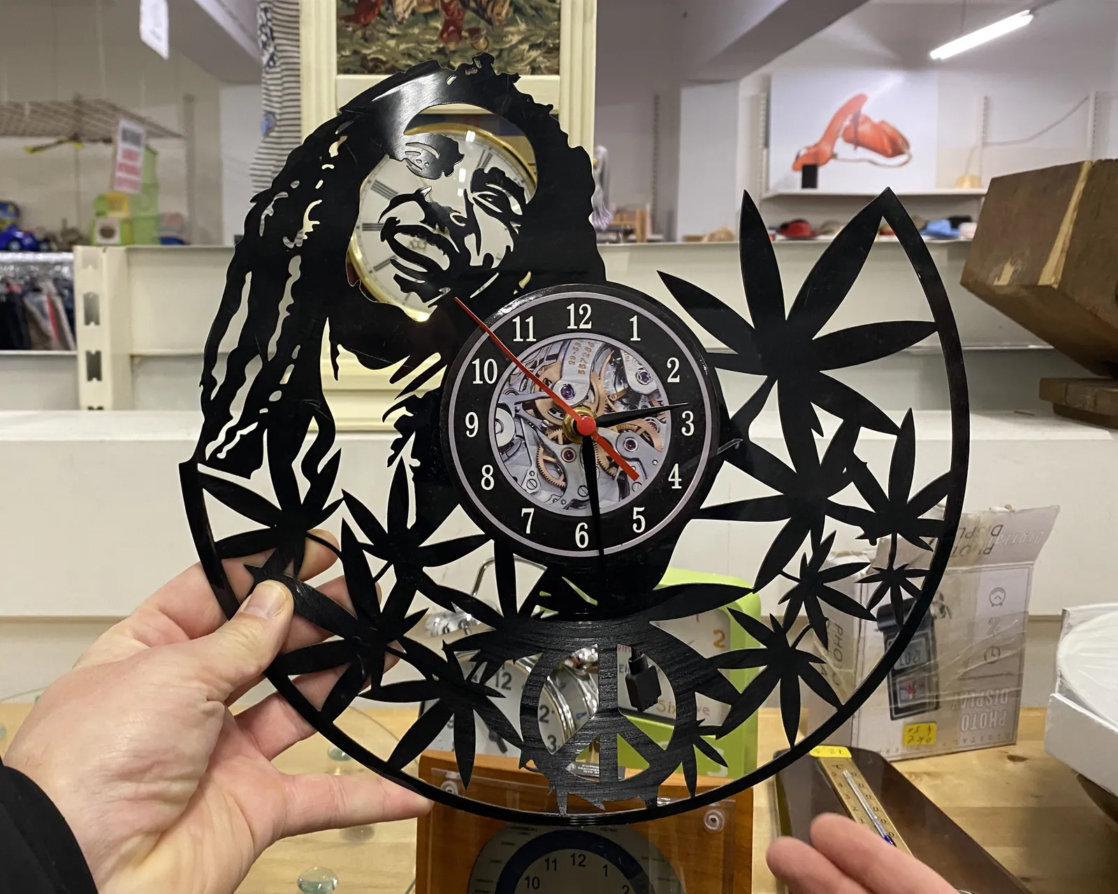 A clock with the image of a smiling Bob Marley surrounded by marijuana leaves. It points at 29 past 2.