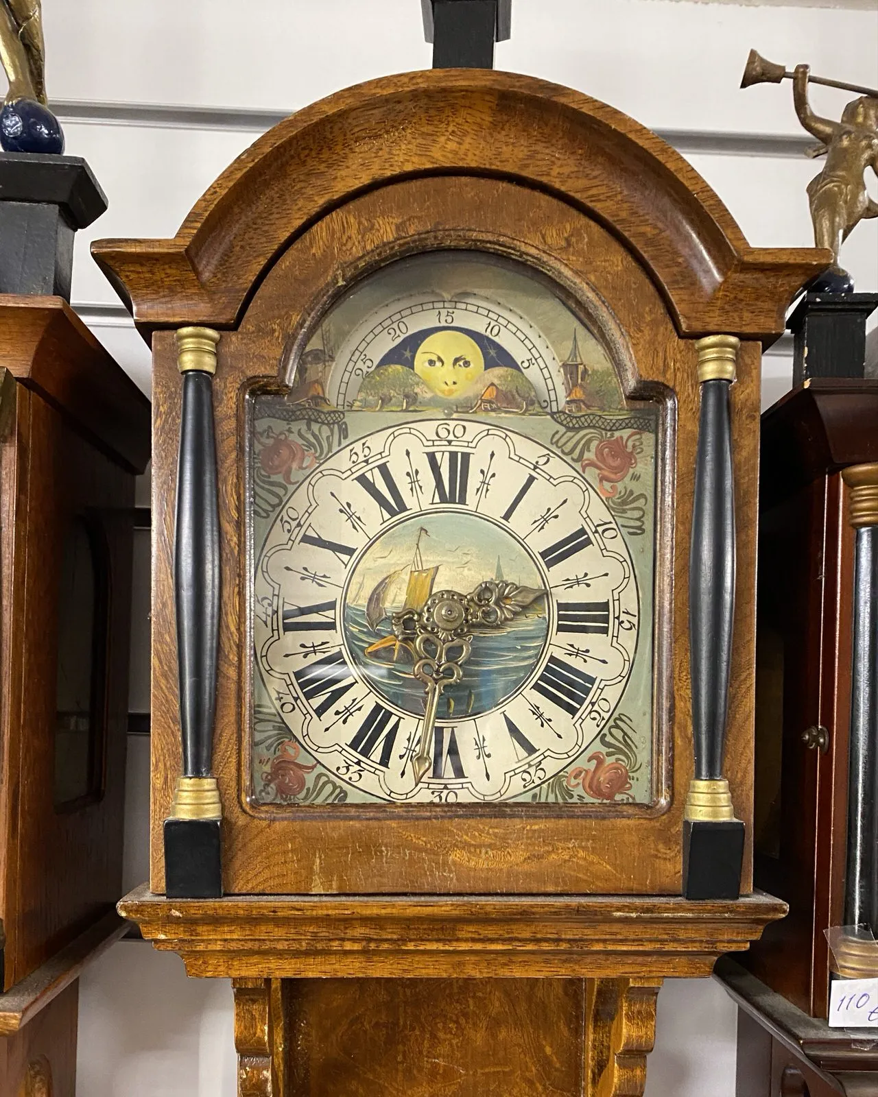An old wooden clock, with a painted face with flowery ornaments on it, points at 31 past 2.