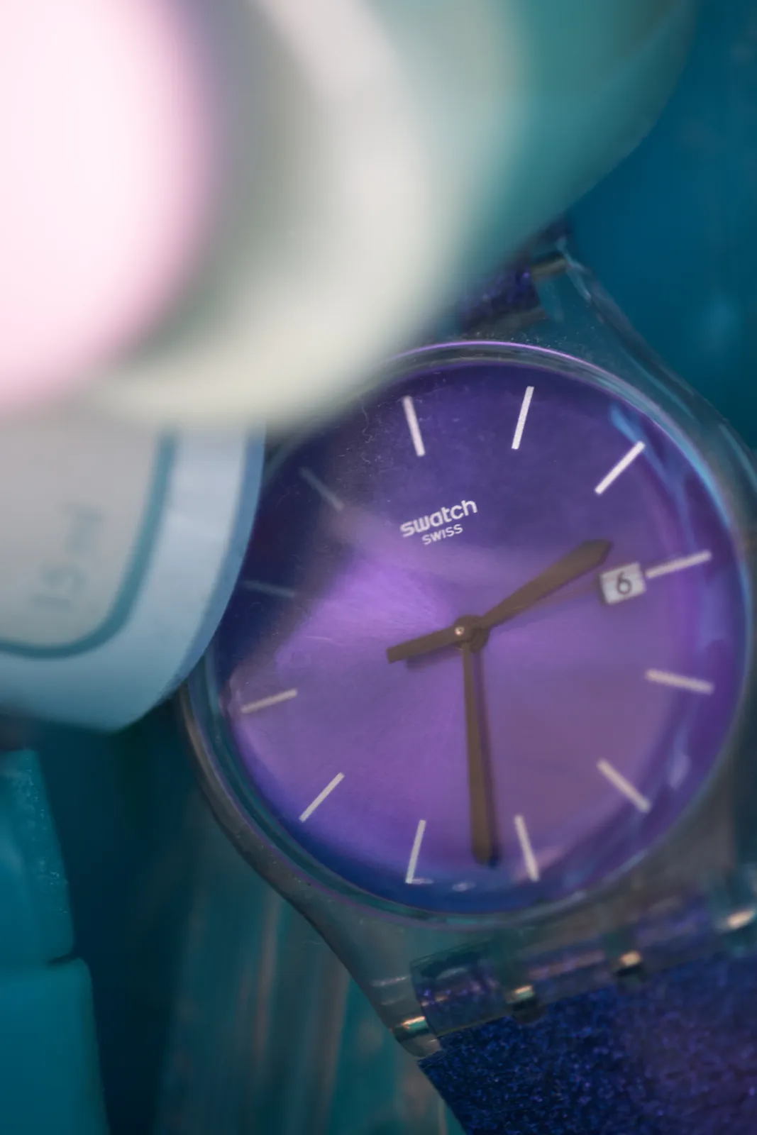 A purple watch laying among some stuff points at 32 past 2.