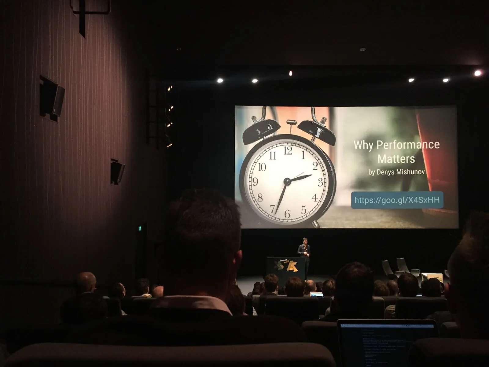 On a slide in a large conference venue there’s a clock that points at 33 minutes past two.