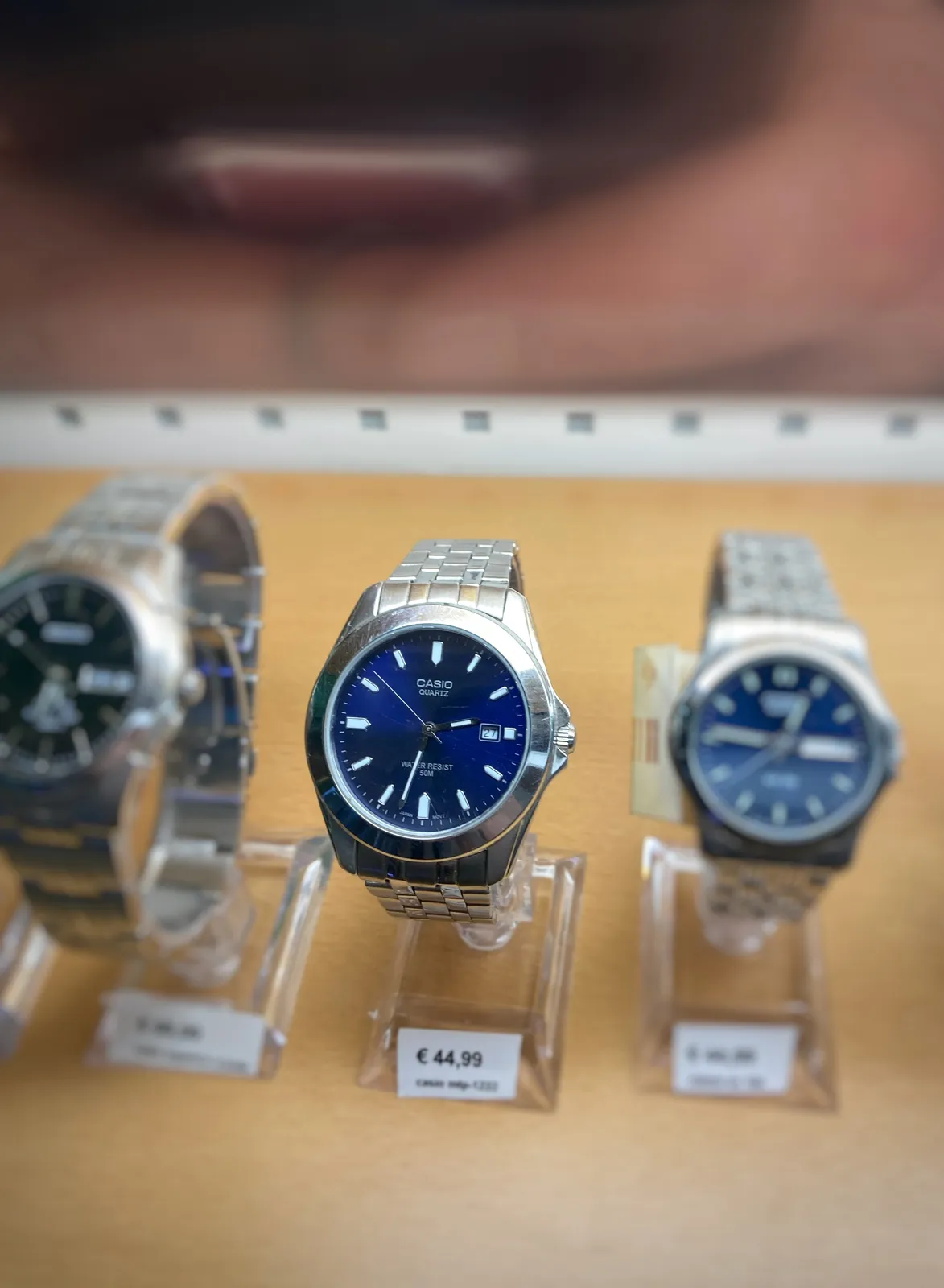 Three metal watches, all with dark blue faces. The one in the middle is in focus and it points at 27 minutes to 3.
