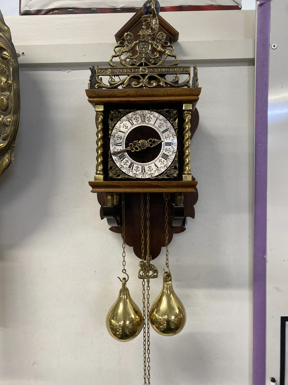 An old, wooden clock with lots of metal ornaments, lions, flowers, and the words Nu Elck Syn Sin, which means Now Everybody Their Desire in old Dutch. It’s two 42 on this clock.