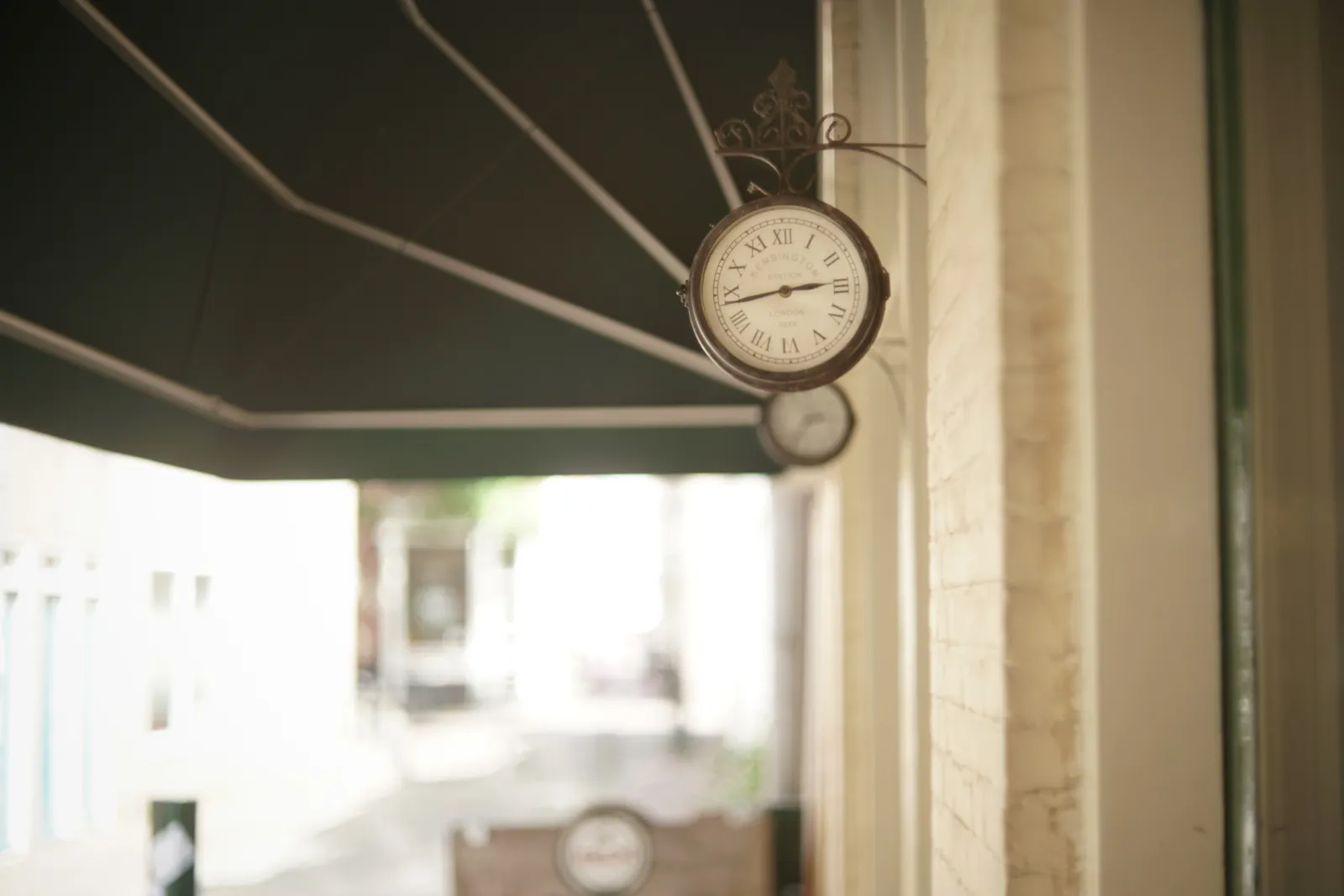 Two clocks attached to a cafe. According to the one that’s in focus it is 17 minutes to three.