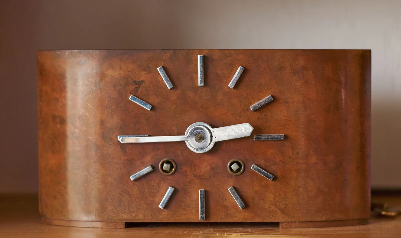 An old wooden table clock points at 16 to three.