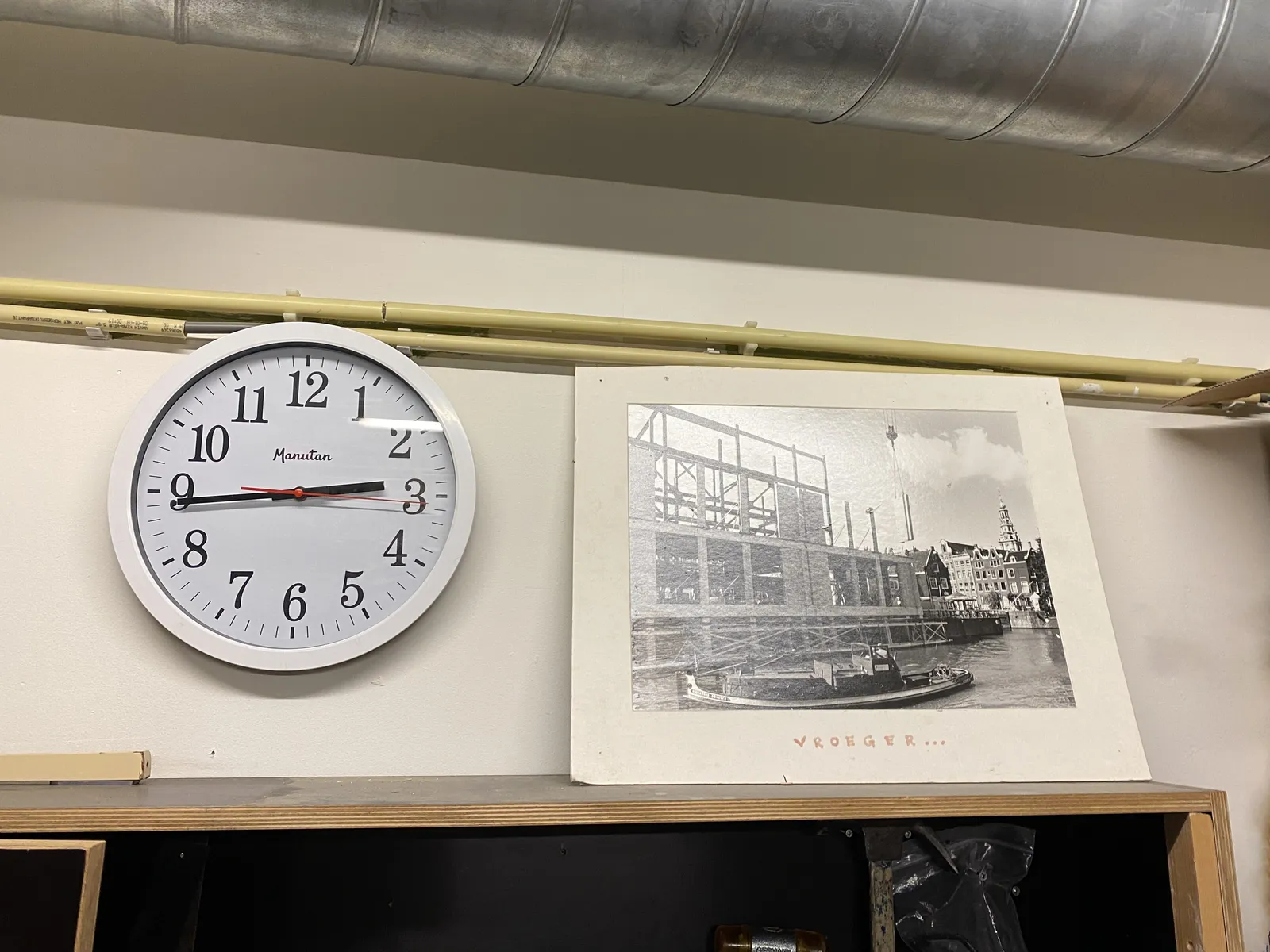 There’s a poster of a boat with the Dutch word Vroeger on it, which would translate to In the old days. Next to the poster there’s a clock which points at 16 minutes to 3. 