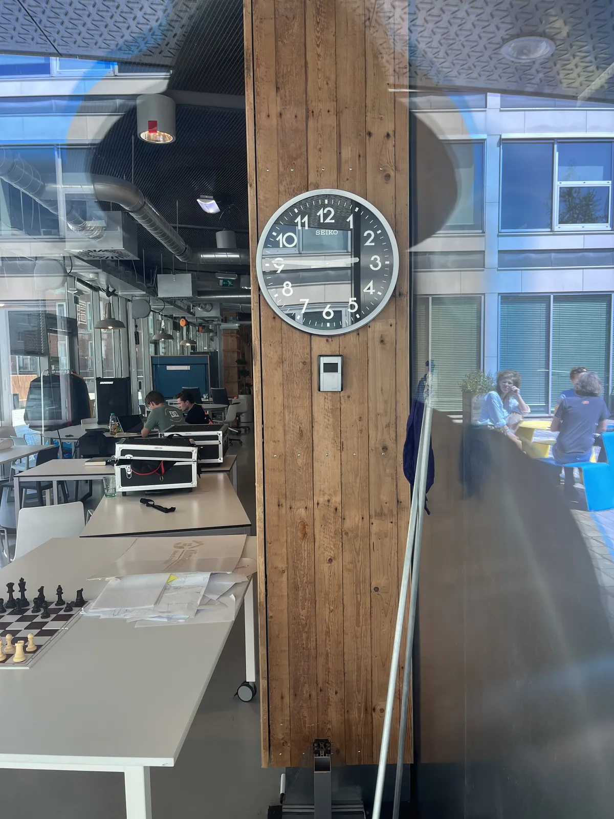 In the reflection of the window you can see that the photographer wears a hat. Inside there’s a clock on the wall. It points at a quarter to three.