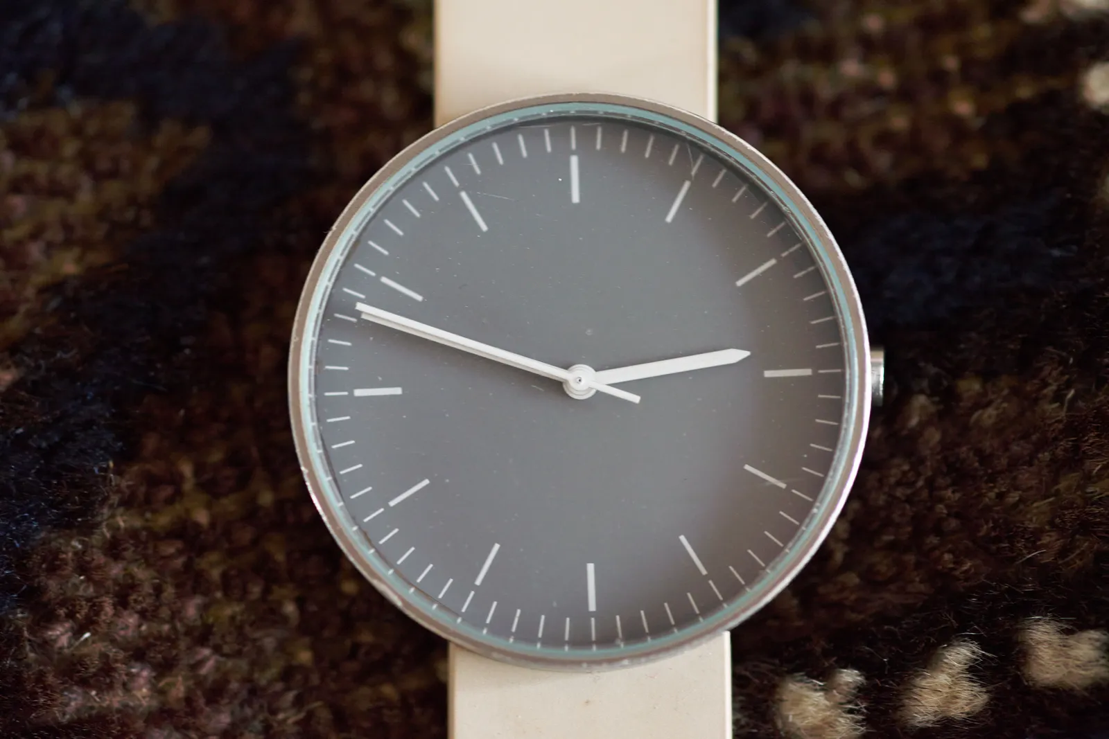 This minimalist gray watch points at 12 to three.