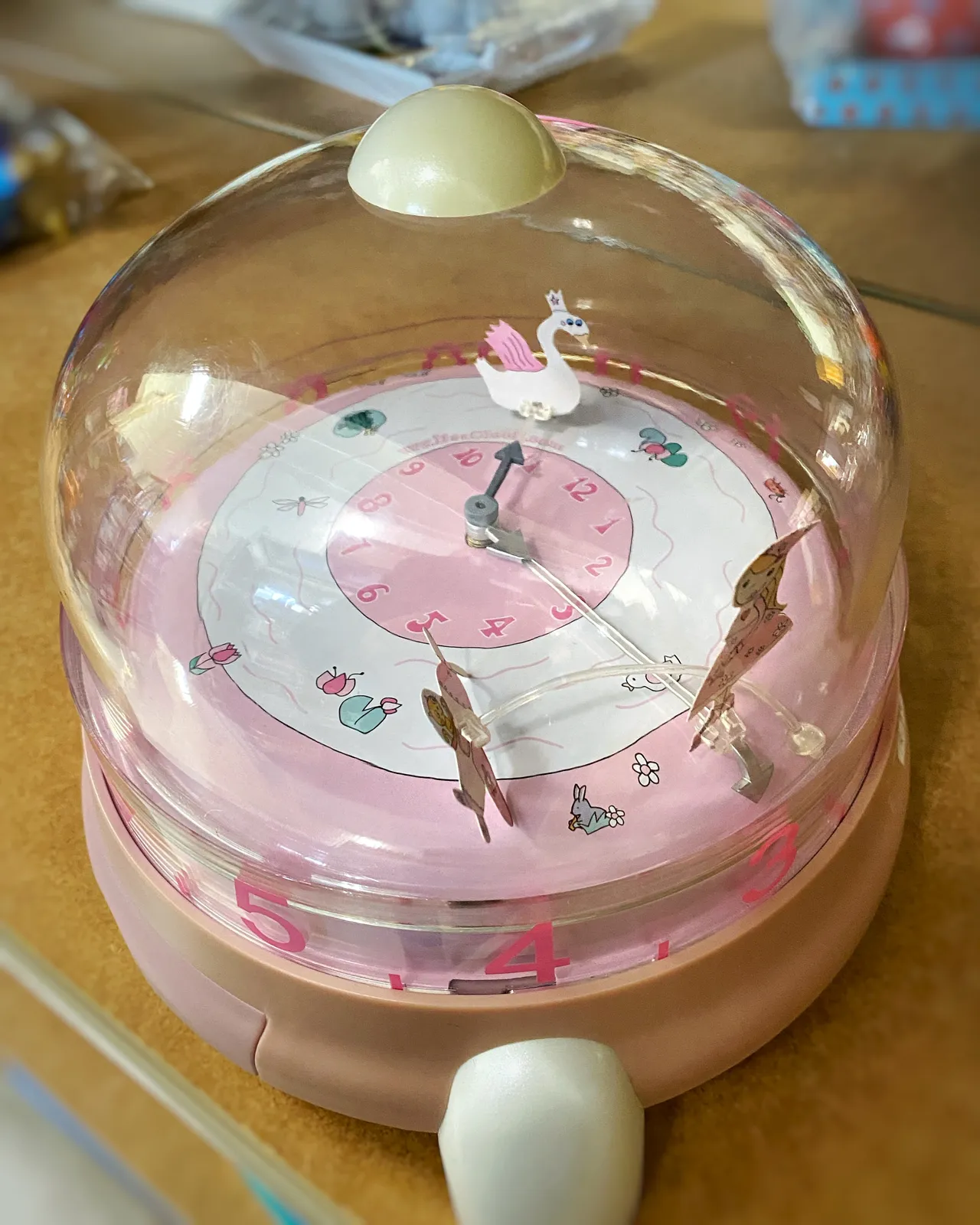 A rather confusing plastic thing, it looks a bit like a pink cake with a plastic dome. In the dome, on the cake there’s a clock. It points at 6 minutes to three.