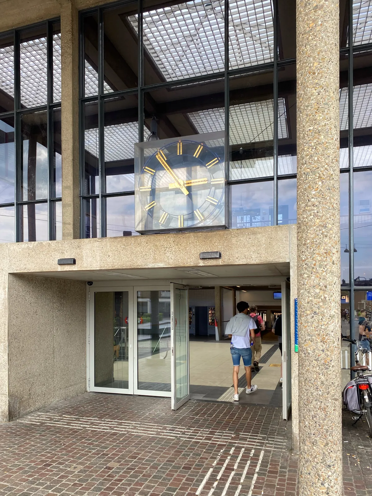 A clock built into the facade of what seems to be a train station. It points at 6 minutes to 3.