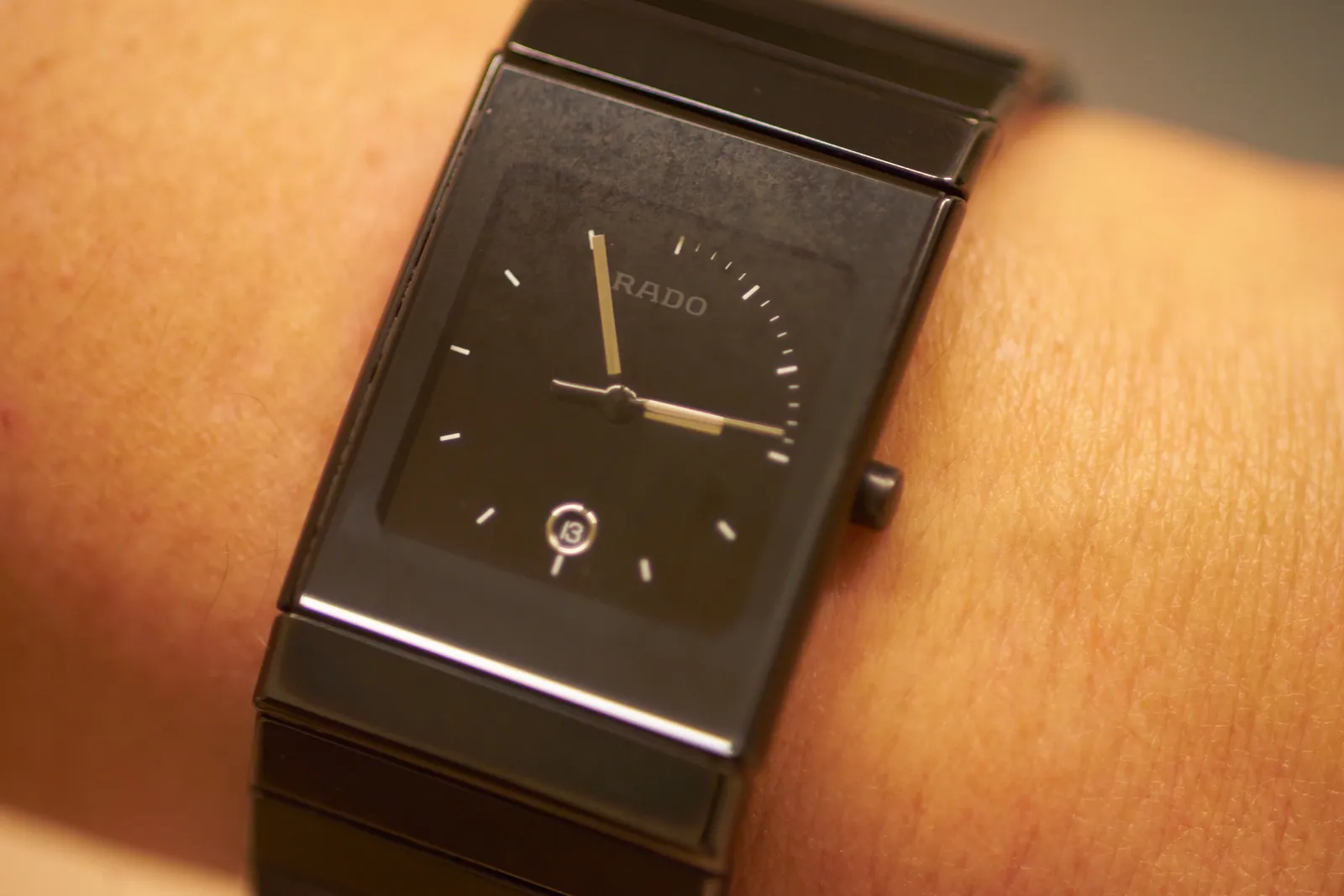 A black Rado wristwatch, on a wrist. It elegantly points at 02:55.  