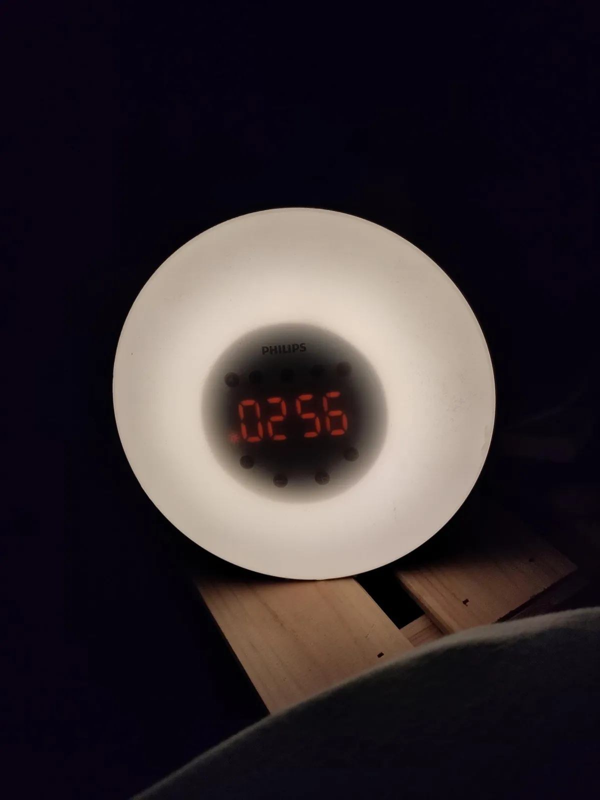 A digital clock with red digits, surrounded by something that looks like a white plastic cap. The clock says it is 02:56