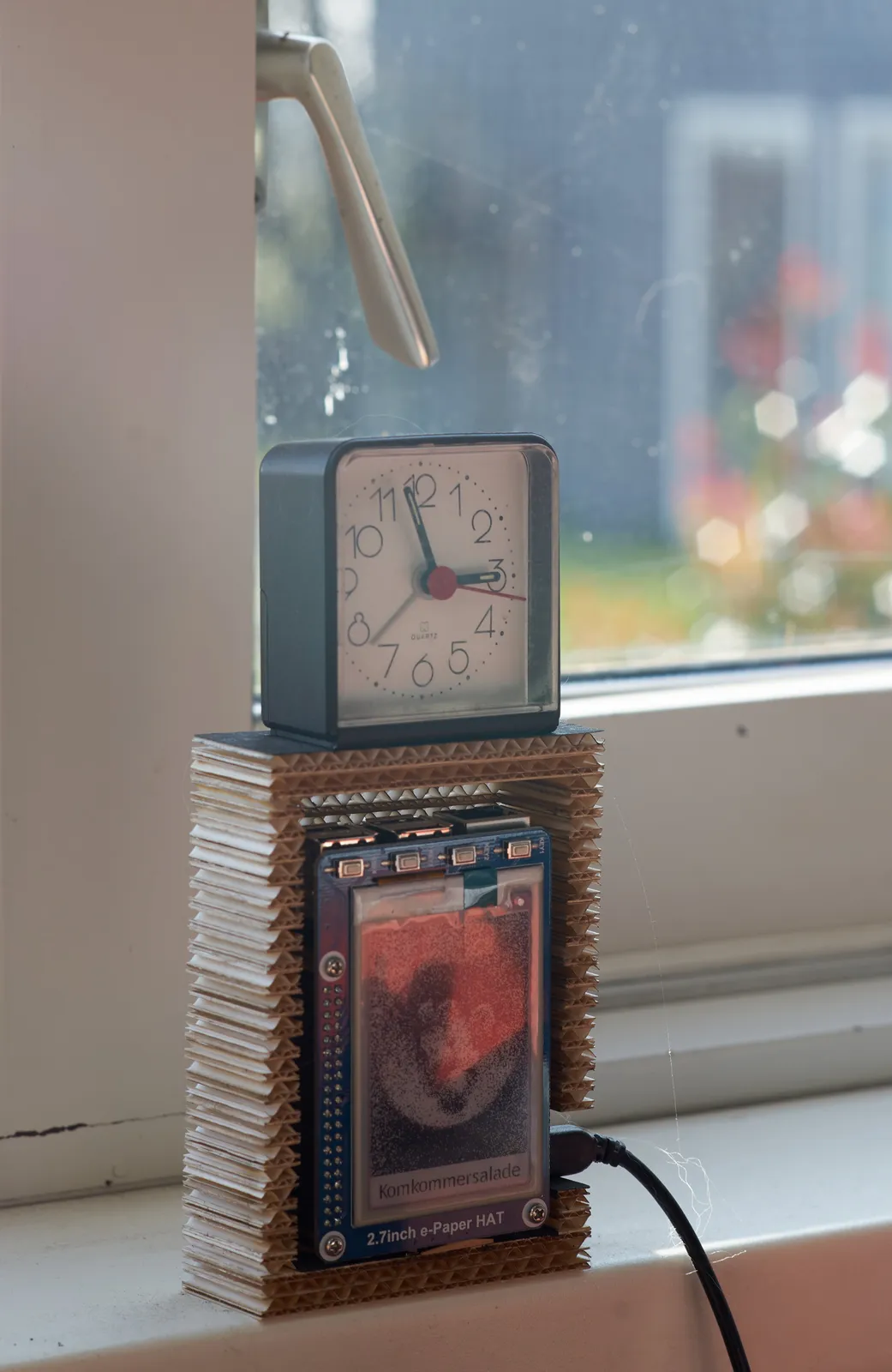 A little clock standing on a work of art points at three minutes to three.