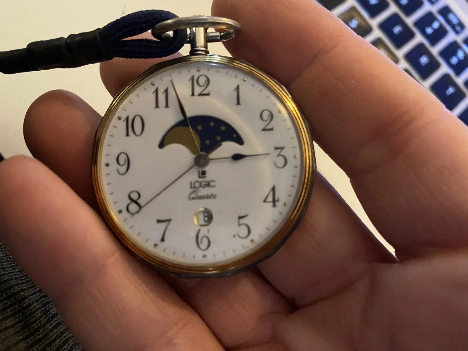 Someone is holding a watch in their hand which points at three minutes to three.