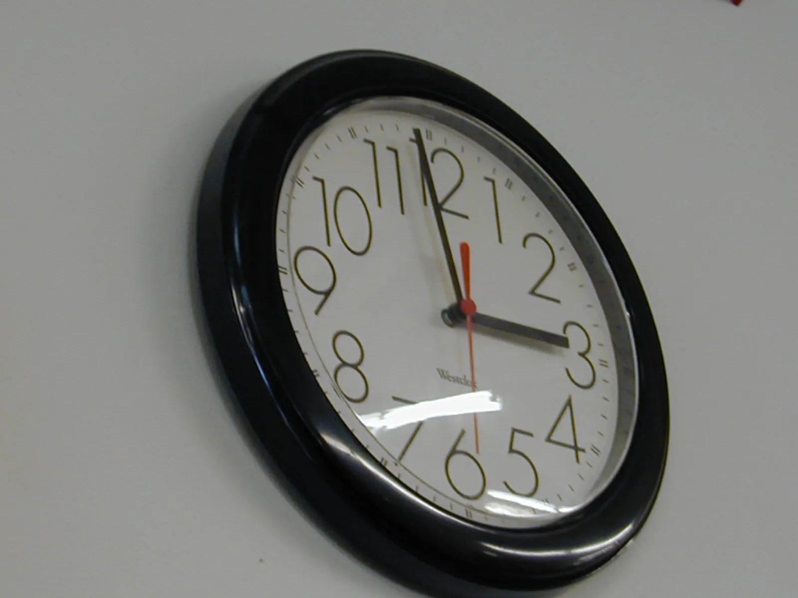 A clock on a wall shows the time. It is 2 minutes to 3.