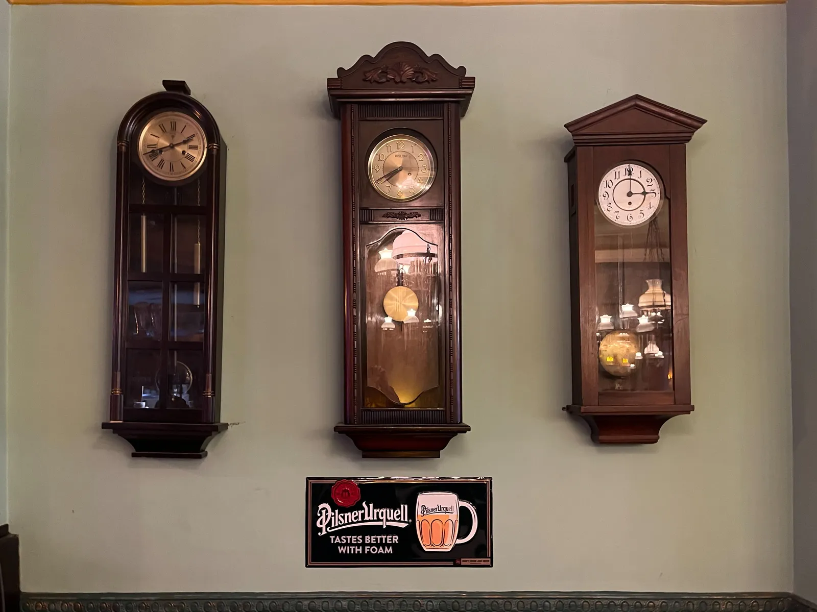 Three antique clocks on a gray wall. The one on the left points at 42 minutes past two. The one in the middle points at 20 to eight, and the one on the right points at three o’clock