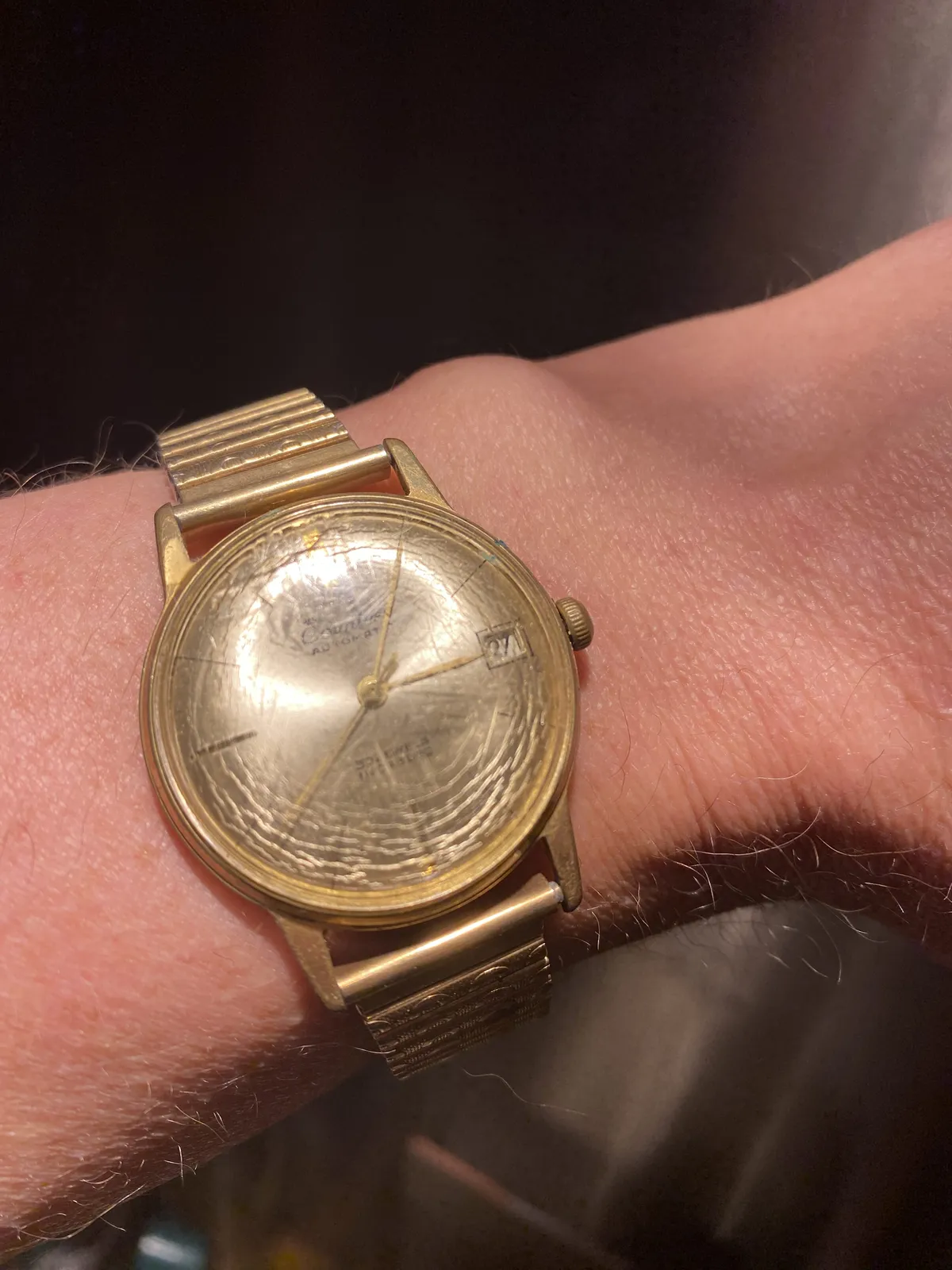 A golden wrist watch that points at 5 past 3.