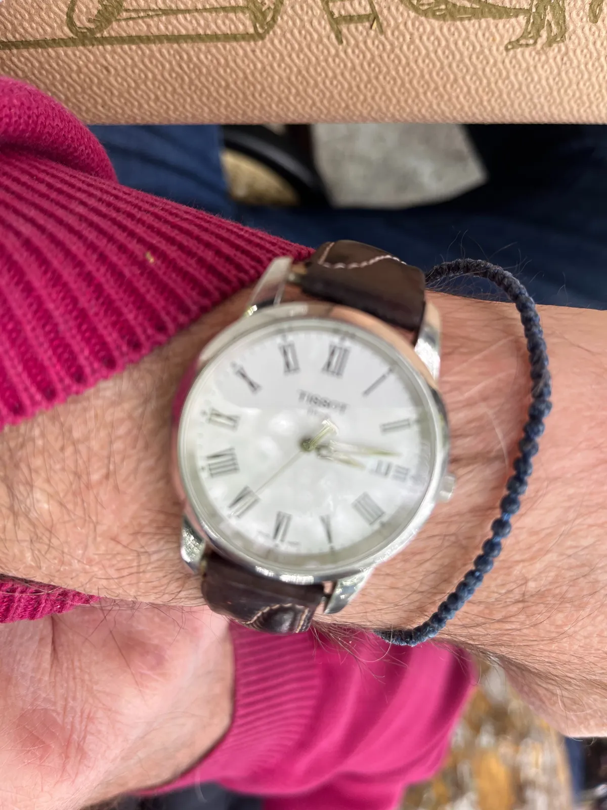 Someone is showing their wrist-watch. It is a bit blurry, but you can see that it points at 13 minutes past 3