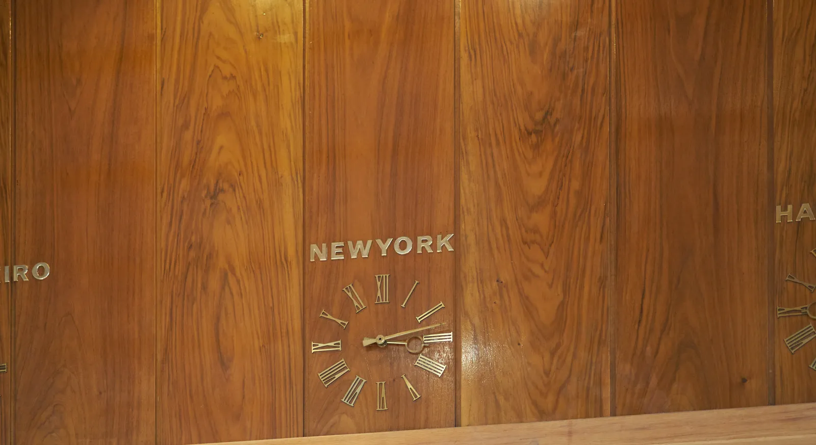 A lathed wall with a built in clock. Above the clock it says New York. The clock points at 13 minutes past three.