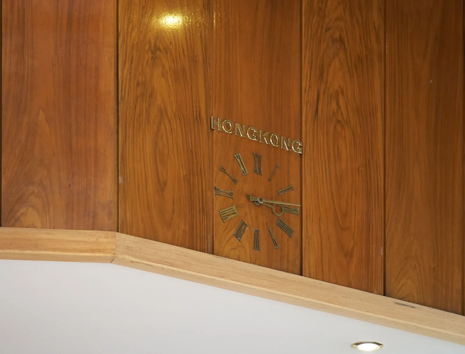 A lathed wall with a built in clock. Above the clock it says Hongkong. The clock points at 14 minutes past 3.
