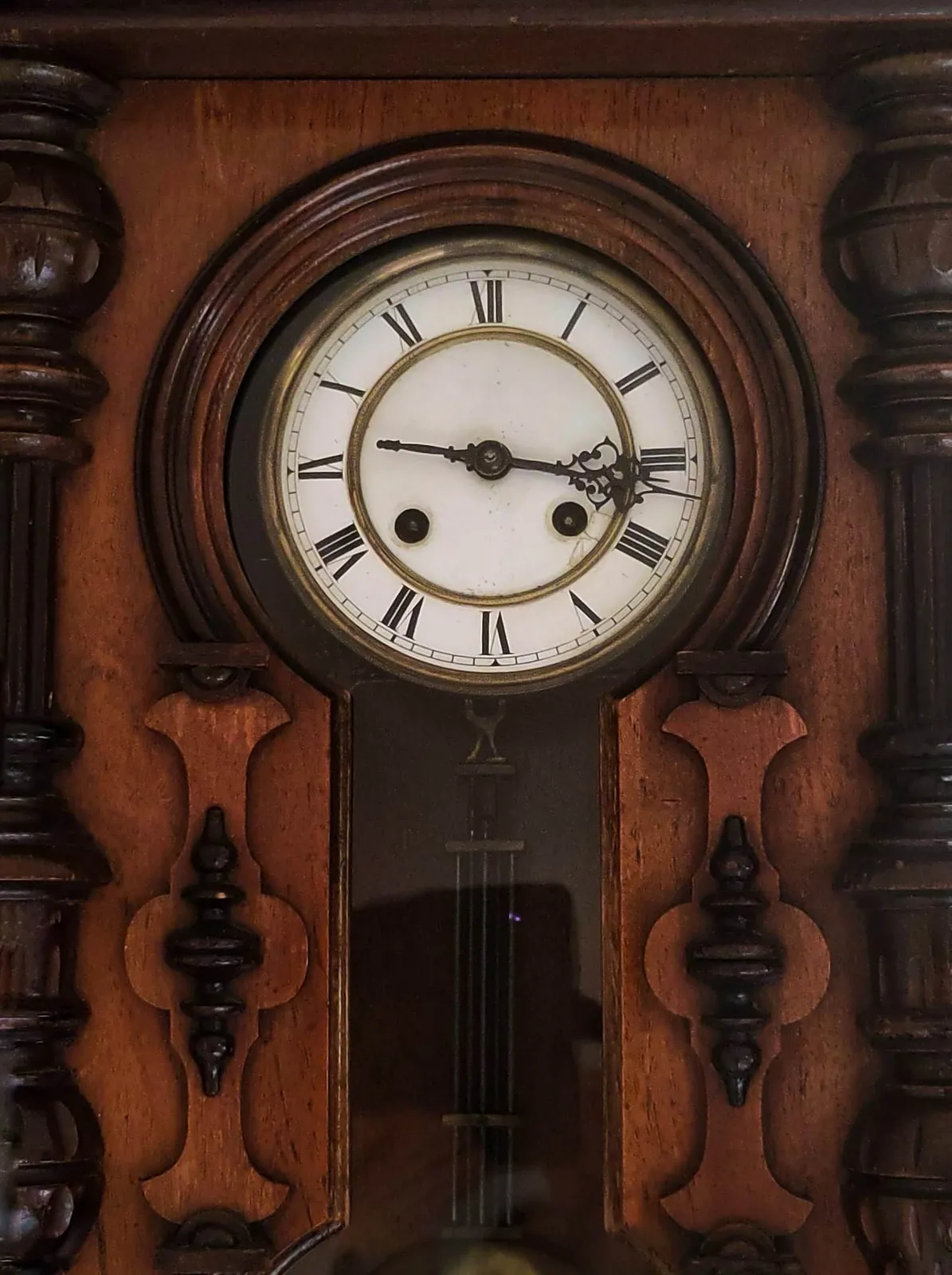An old wooden clock, with some nice woodwork. The clock points at 17 minutes past 3.