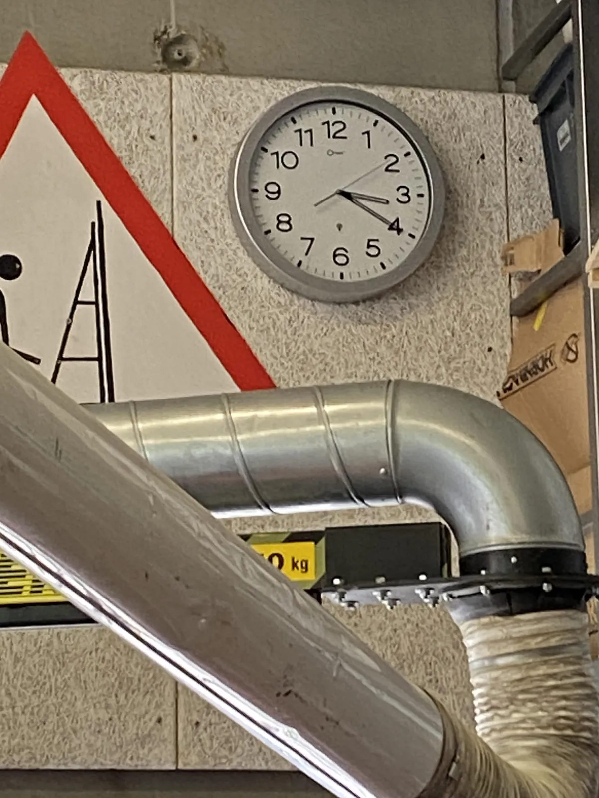 A few metal pipes cover half an alert sign, so it’s unclear what it warns for. They don’t cover the clock on the wall though, which indicates that it’s three 20. 