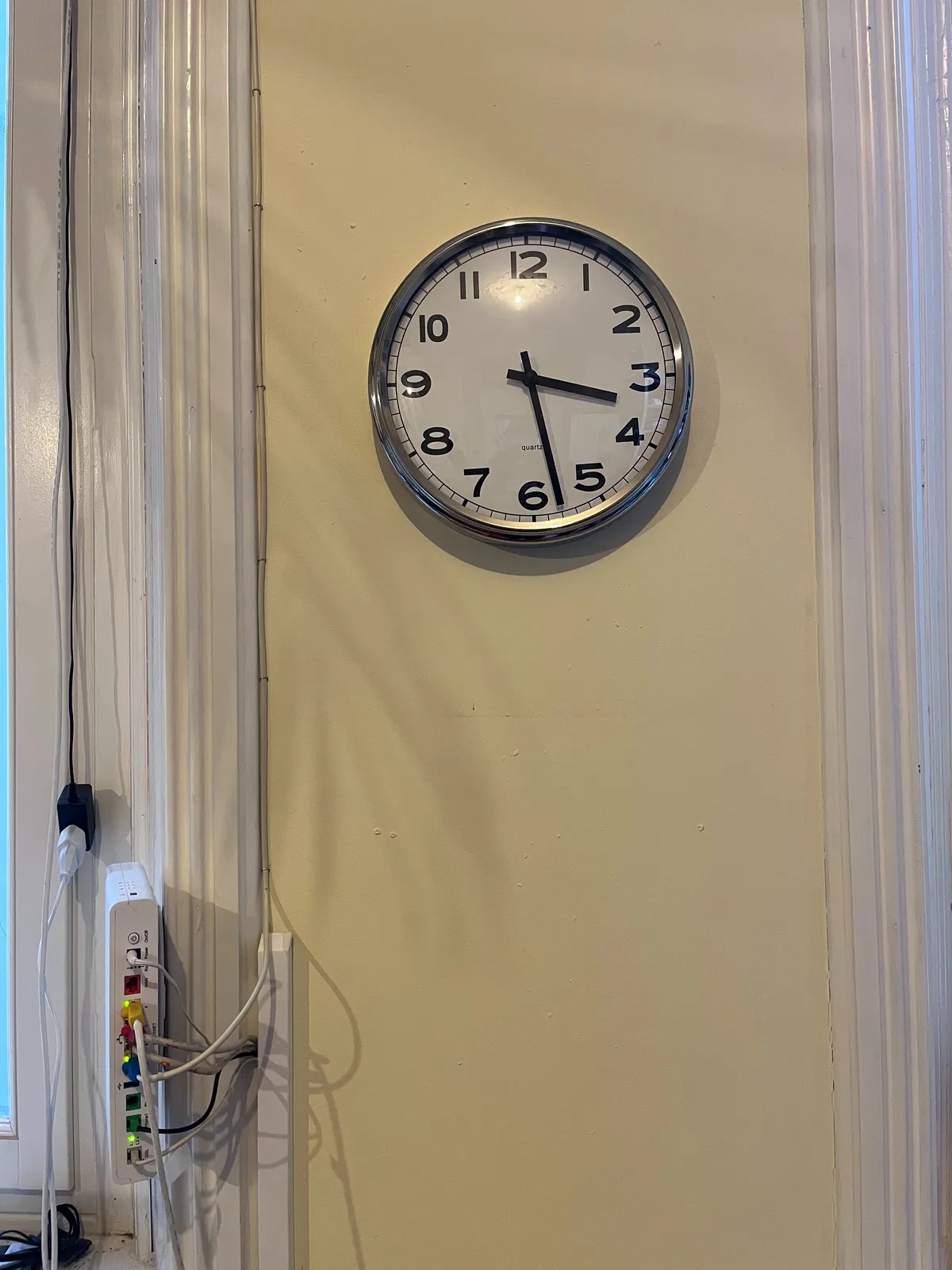 There’s a modem with lots and lots of wires in it at the bottom left of this picture. In the center there’s a clock that points at 28 minutes past 3.