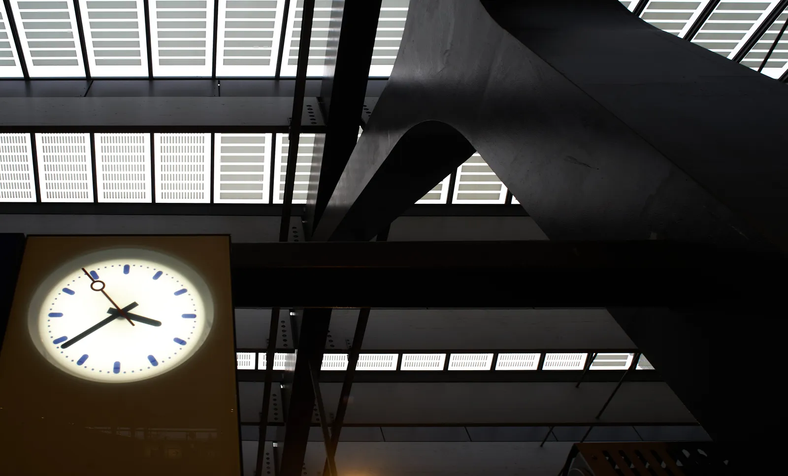 A large pillar in the right corner, supporting the glass roof. In the bottom left corner of the picture there’s a clock that points at 38 minutes past 3.