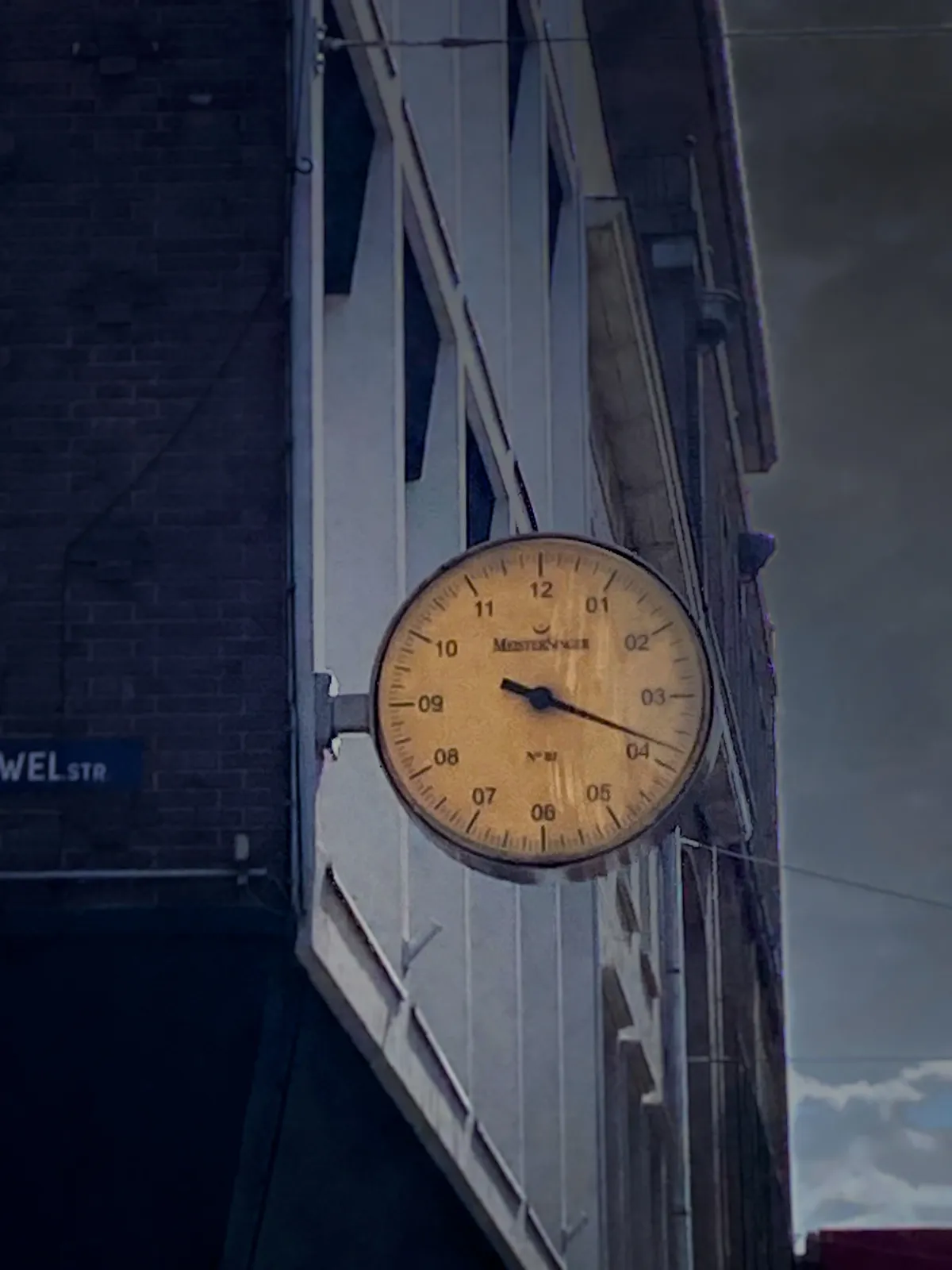 A clock attached to a building. It has just one hand, the hour hand, but it is pretty detailed, so it’s clear that it is a quarter to 4.