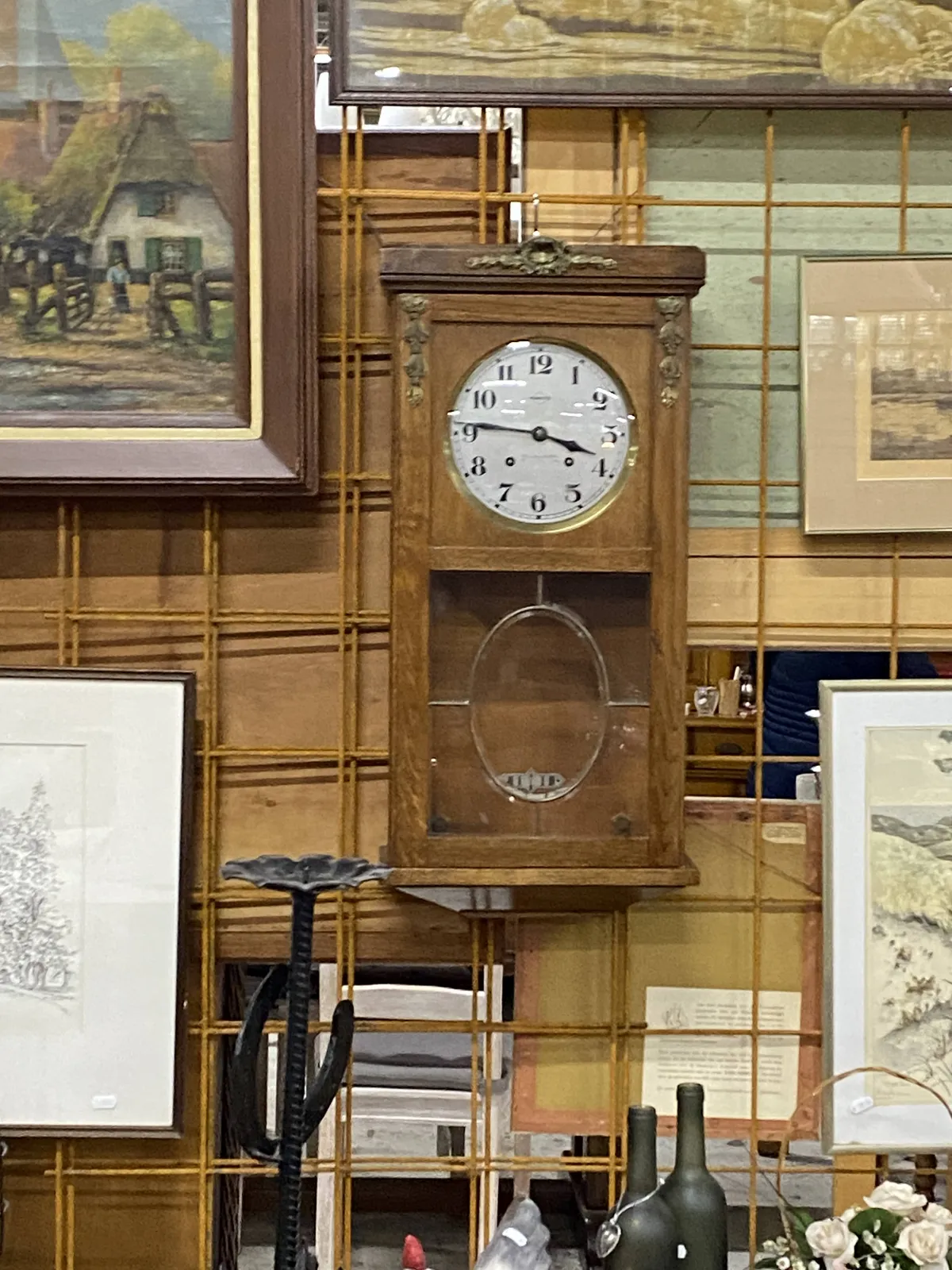 Old paintings for sale, and an old wooden clock. It points at 14 minutes to 4.