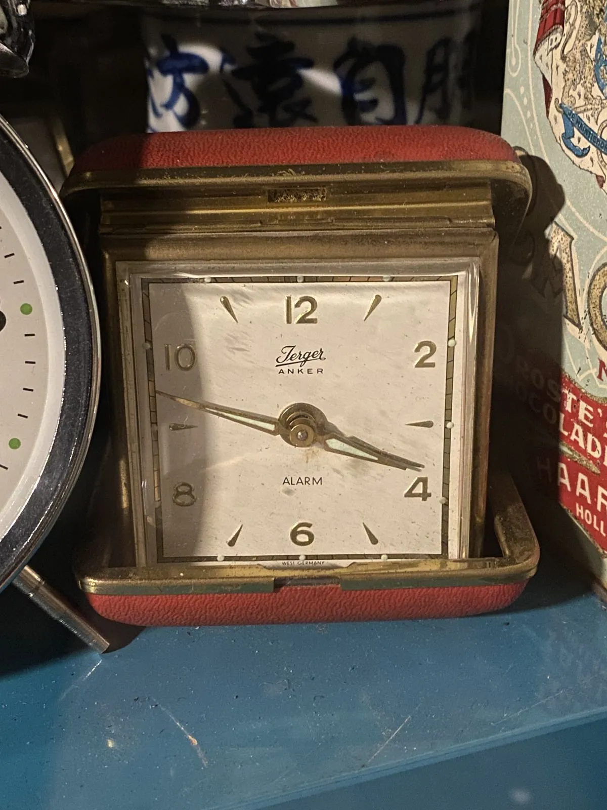 This old compact travel clock points at 13 minutes to four.