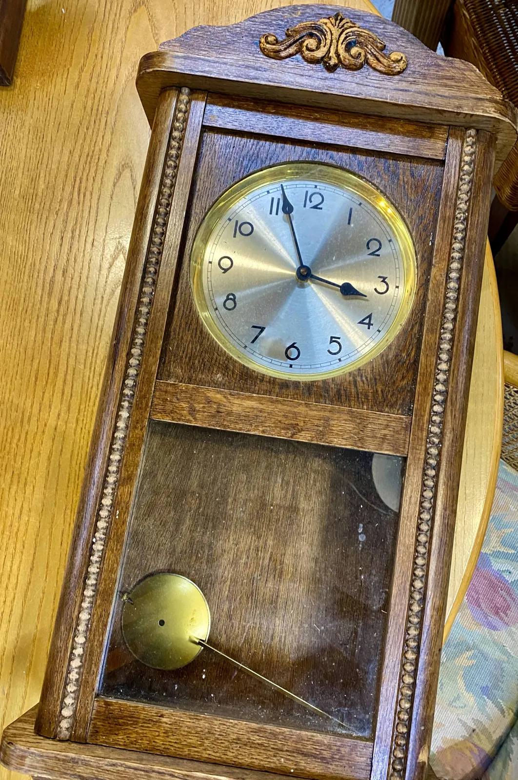 An old wooden clock. It points at 4 minutes to 4.