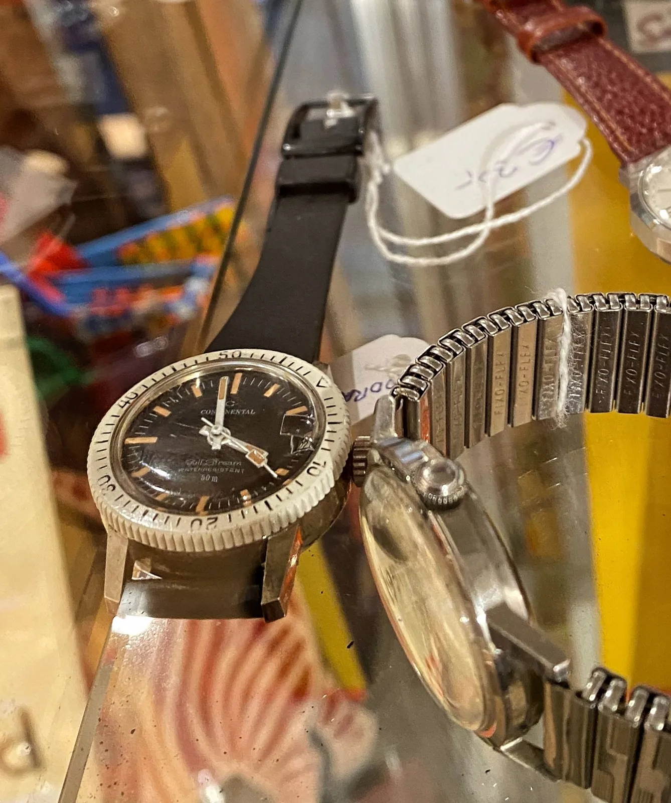 A few wrist watches on a glass plate. Just one of them is clearly in focus. It points at one minute to 4.