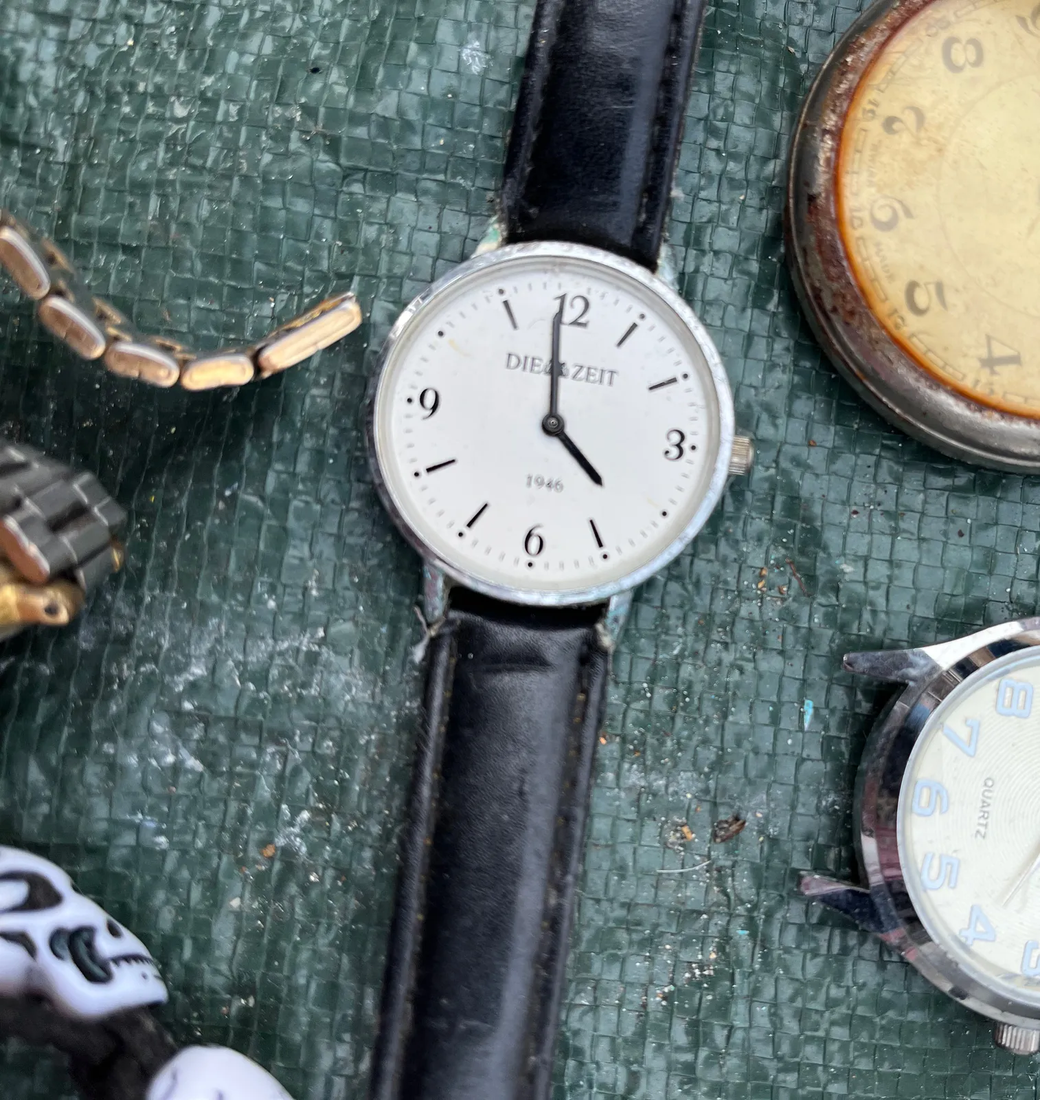 A watch surrounded by other watches points at 1 minute to 4. It’s not possible to see the exact time on the other watches.