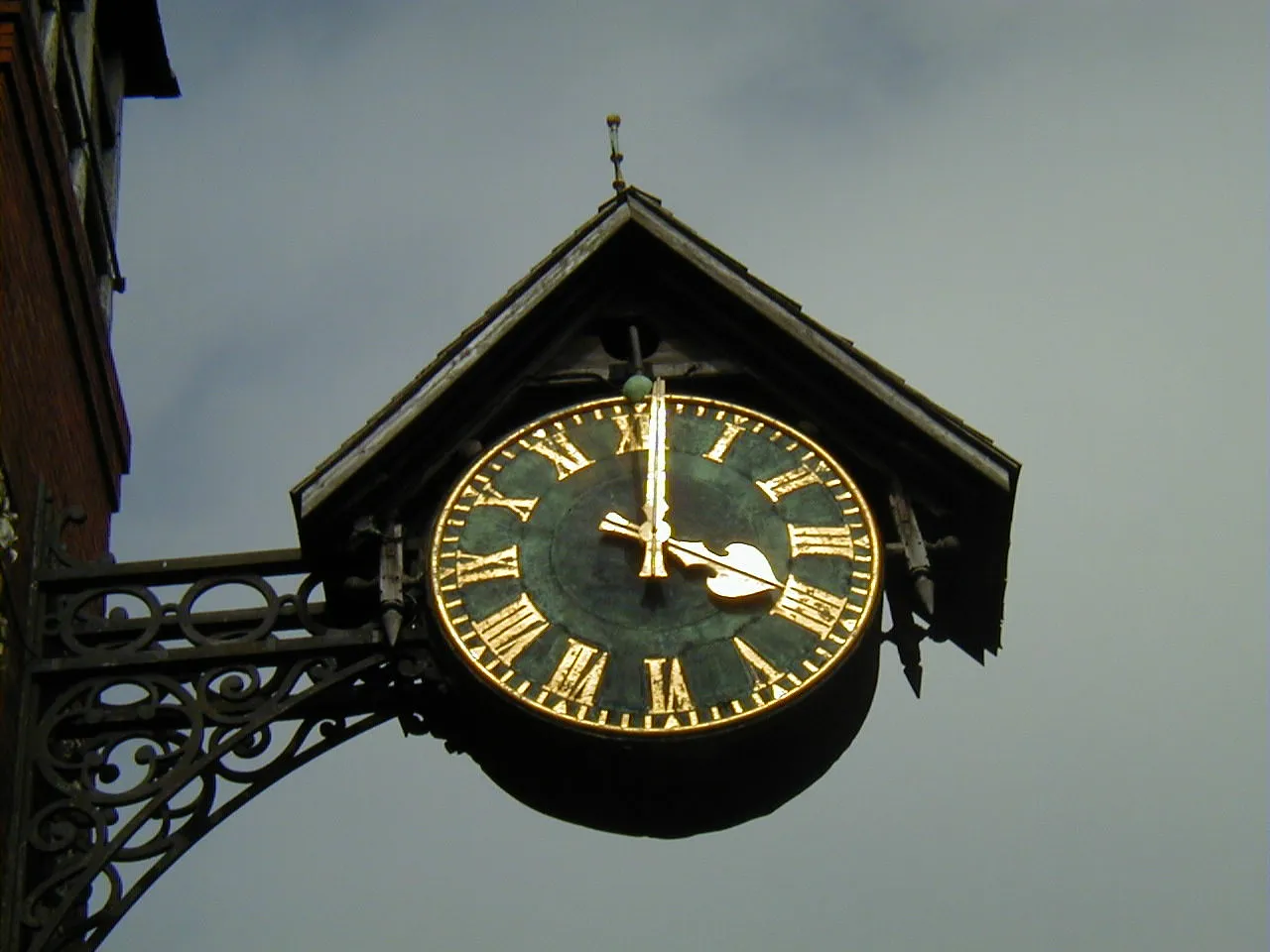 A clock with its own roof, and gold, Latin numerals. It says it is one minute past four.