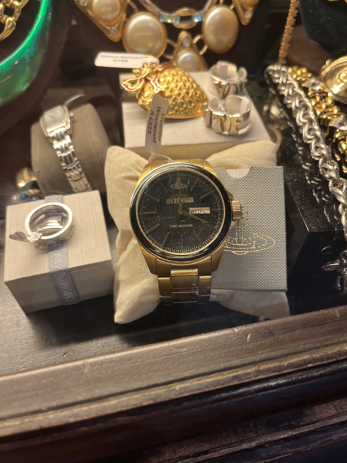 All kinds of jewelery for sale. Among these items is a golden watch, by Vivianne Westwood. It points at one minute past four.