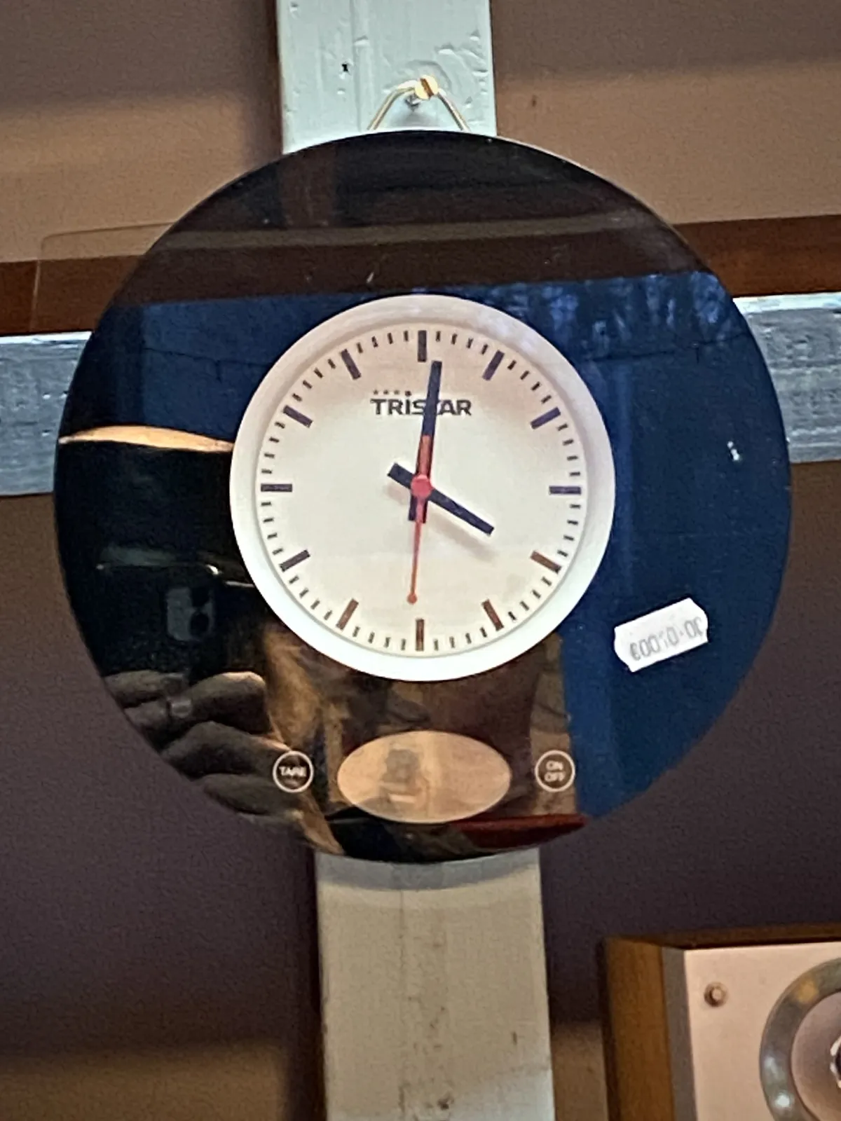 A simple clock, the word Tristar is printed on its face, points at one minutes past 4.