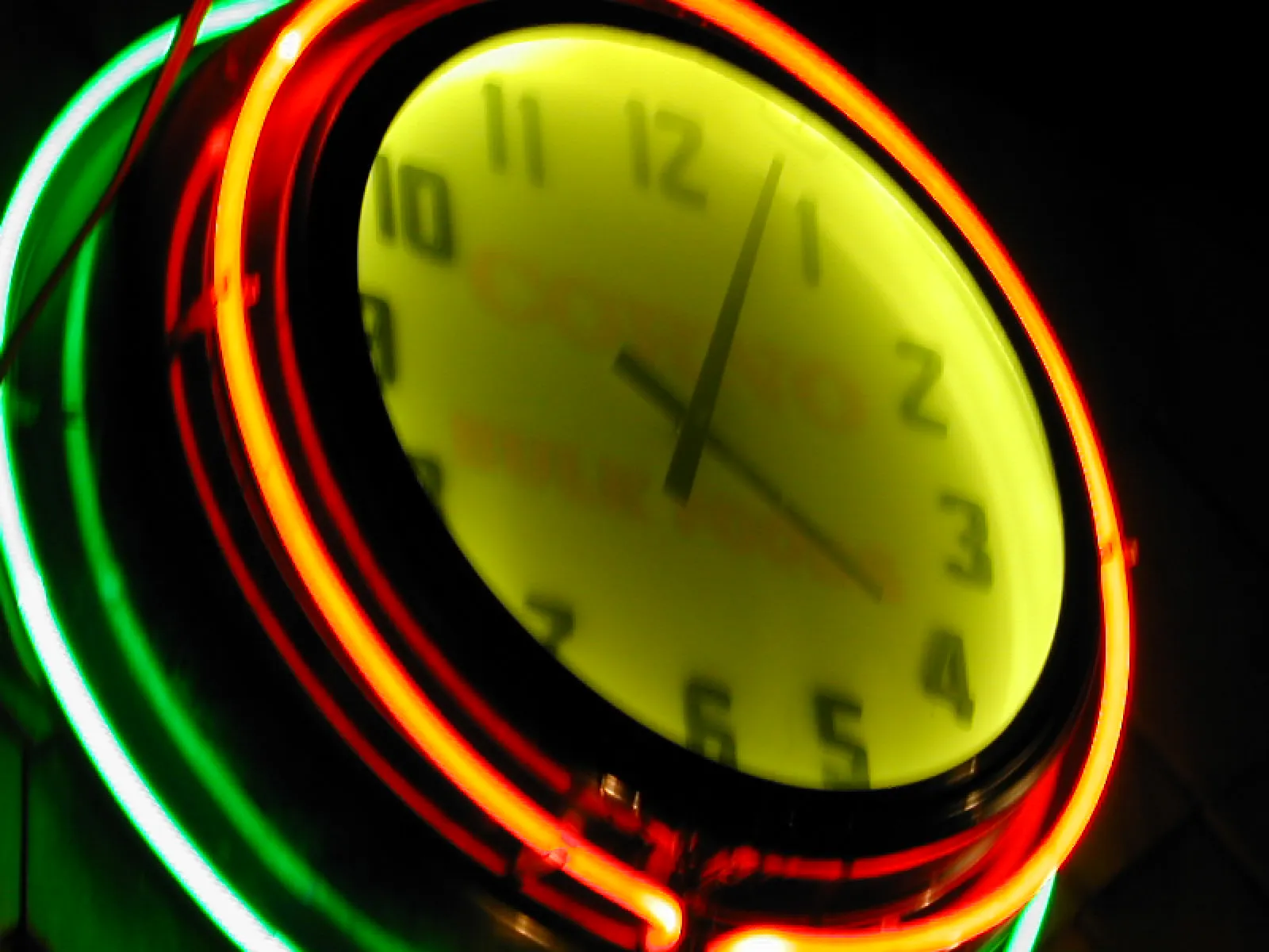 A clock in a multi-coloured neon frame points at 4 minutes past 4.