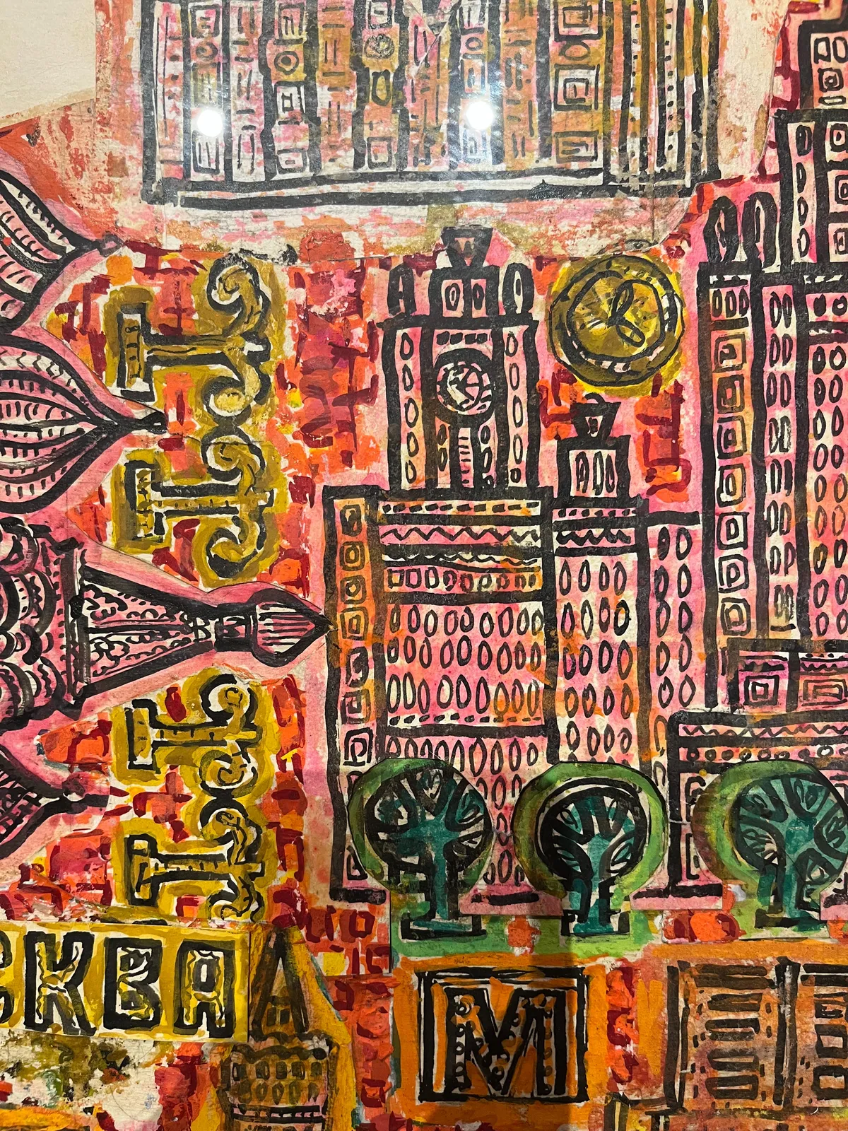 A detail of a colourful, pretty busy painting. It seems like a simplified map of Moscow. There are all kinds of buildings on this painting. On two of these buildings there’s a clock. They both seem to point at approximately 4 minutes past 4
