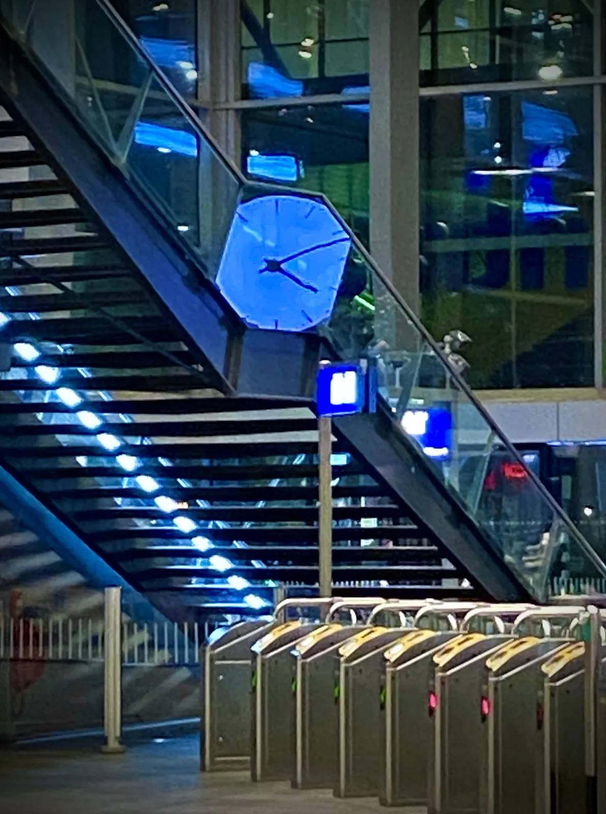 On a train station there’s an extremely weird, very blobby reflection of a clock in a glass panel. It seems to point at 11 past 4.