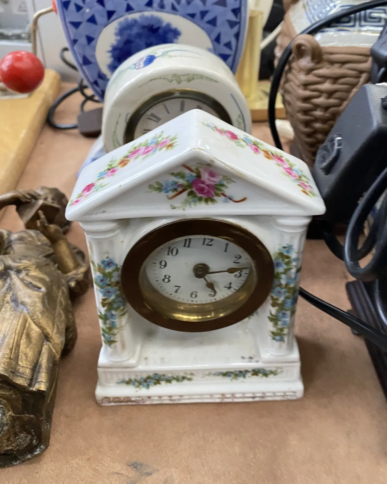 A ceramic — or is it plastic? — clock in the shape of a house on a flea market points at 12 minutes past 4.