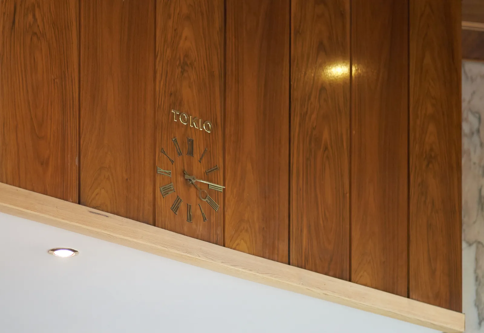 A lathed wall with a built in clock. Above the clock it says Tokio. The clock points at 14 minutes past 4.